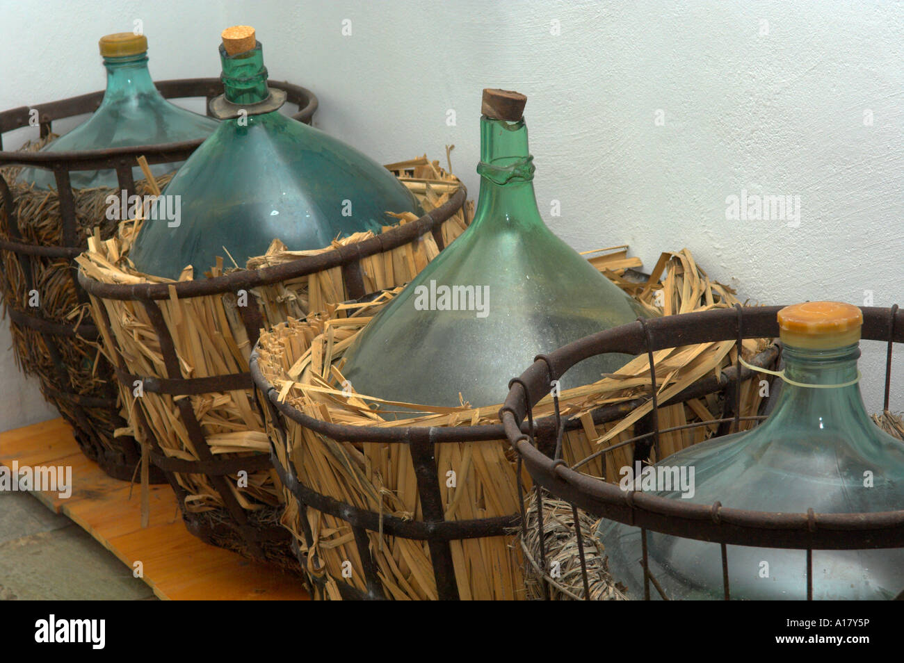 Old style blown green glass carboys in metal framed wicker baskets in