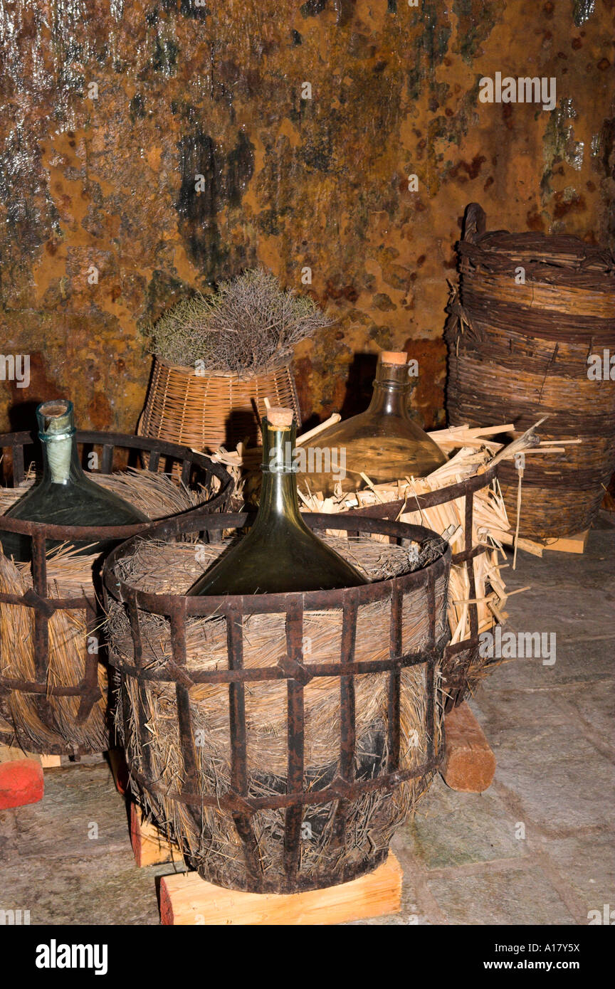 Old style blown green glass carboys in metal framed wicker baskets in