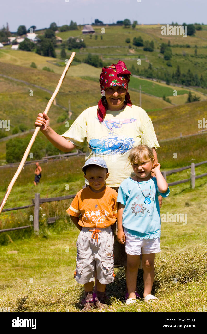 Grandmother with her grandchildren during haymaking harvest in Marisel village, Apuseni Mountains Transylvania Romania Stock Photo