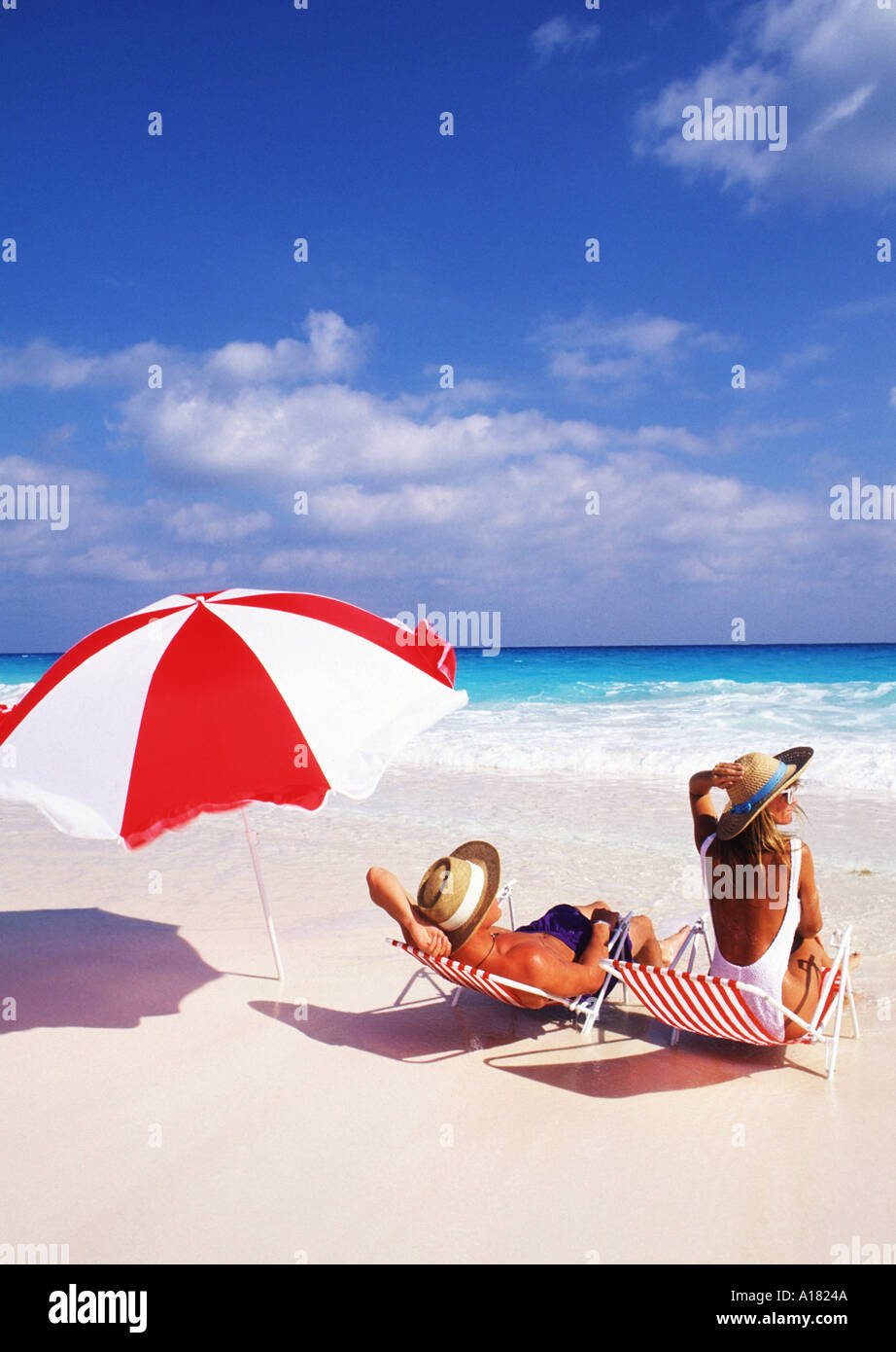 Couple relaxing on beach with lounge chairs and umbrella Stock Photo ...