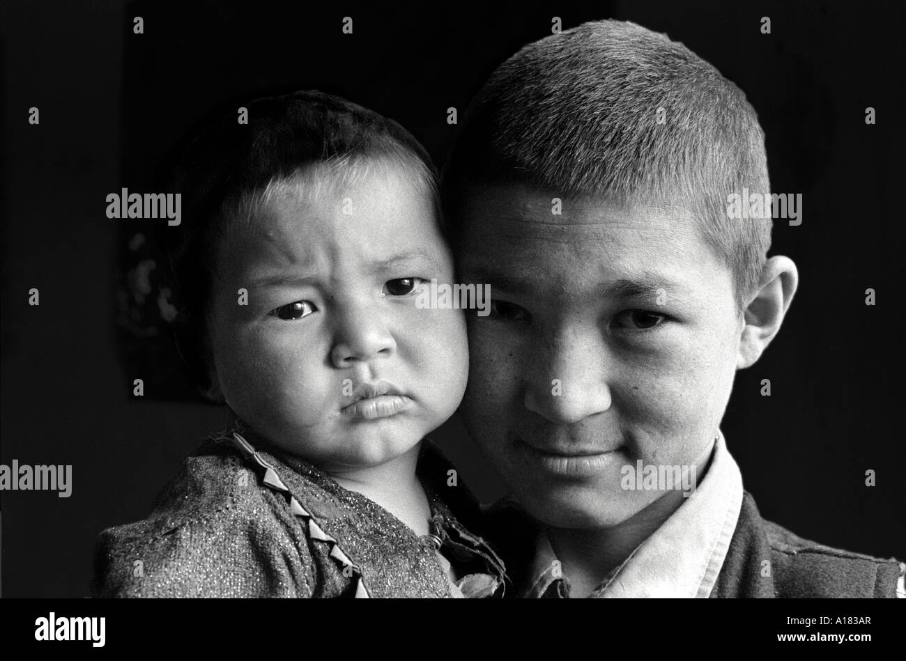B/W close-up portrait of an Afghan boy and his baby sister. Kabul, Afghanistan Stock Photo