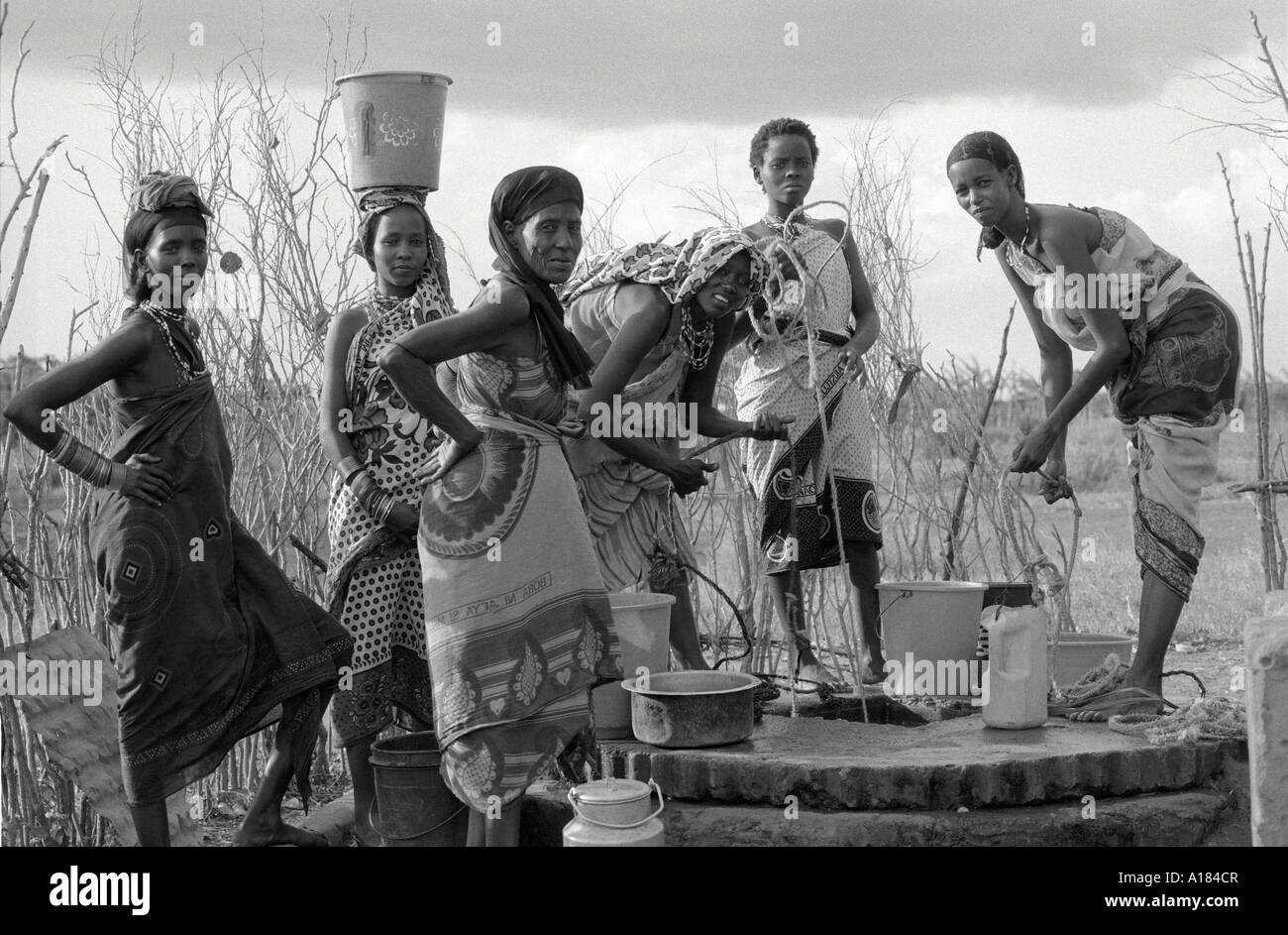 B/W of rural Oromo women in traditional dress drawing water at a well. Wajir, N.E. Kenya Stock Photo
