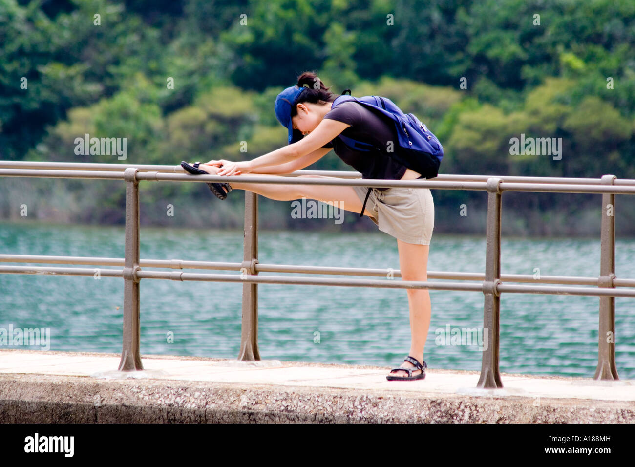 Young Woman Stretches Out on Bridge at Tai Tam Reservoir Hong Kong China Stock Photo