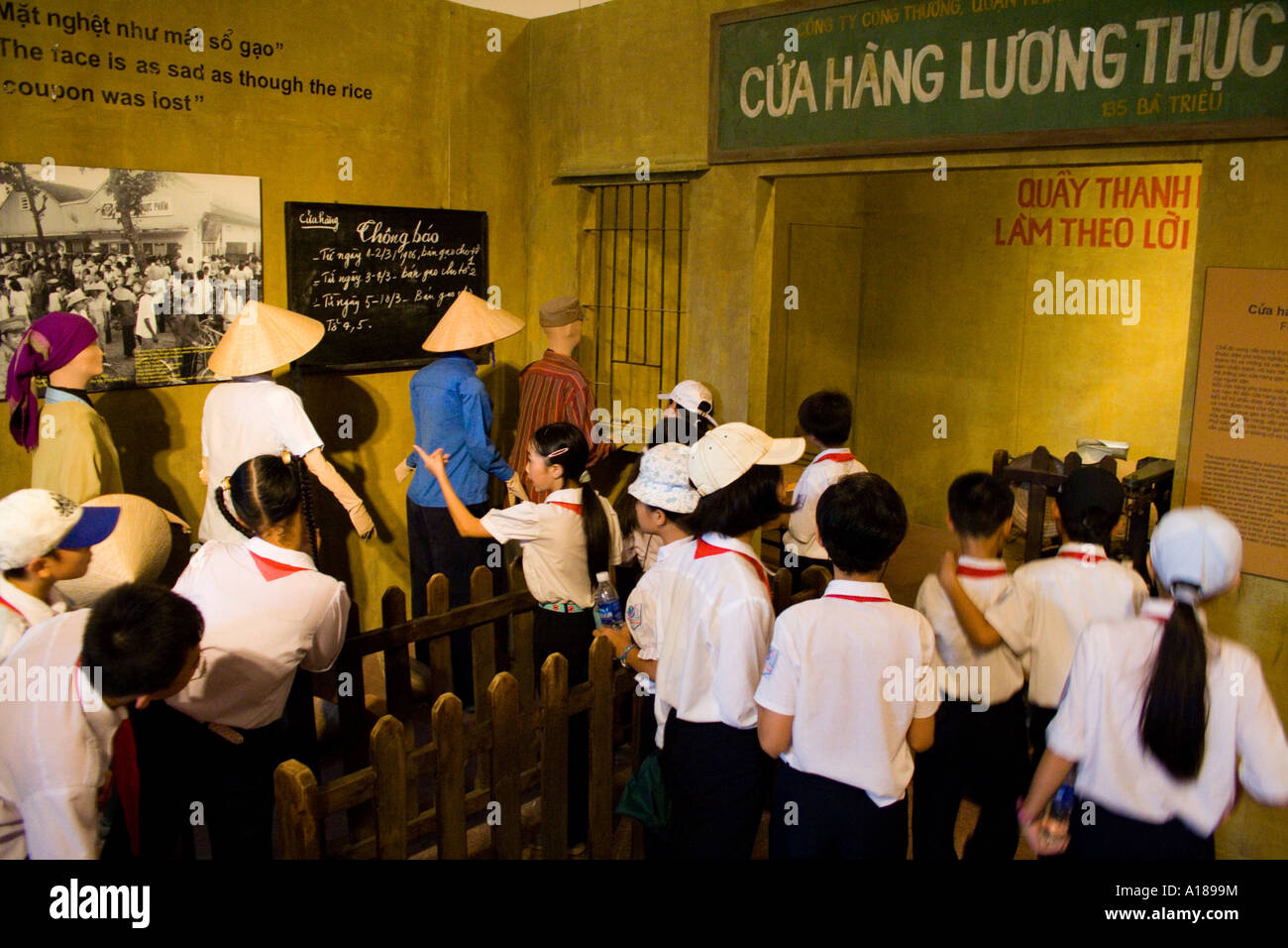 2007 Uniformed School Children Walk through a Display on Ration Card Lines in Early Communism Days of Vietnam Stock Photo