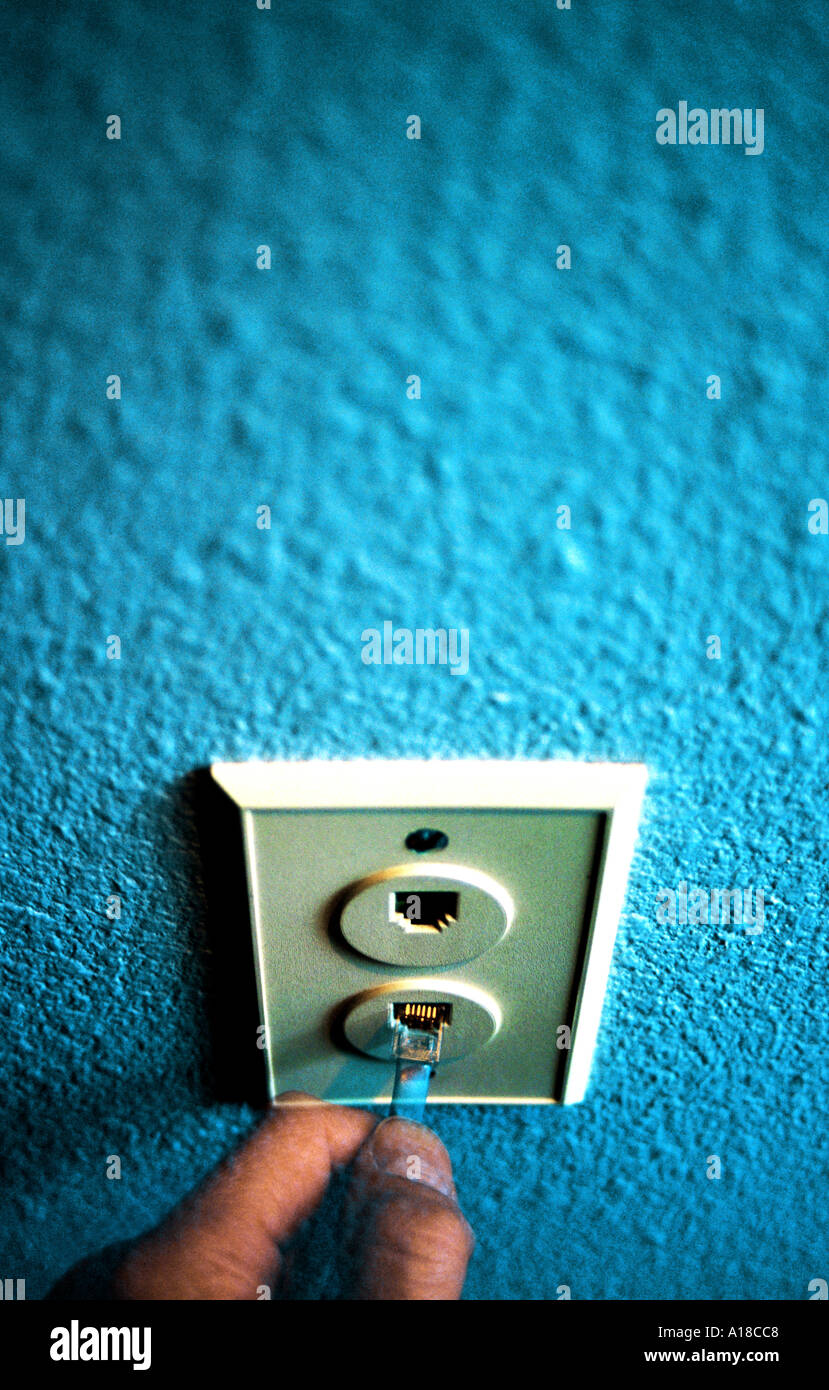 Hand plugging phone cord into wall jack multiple exposure Stock Photo