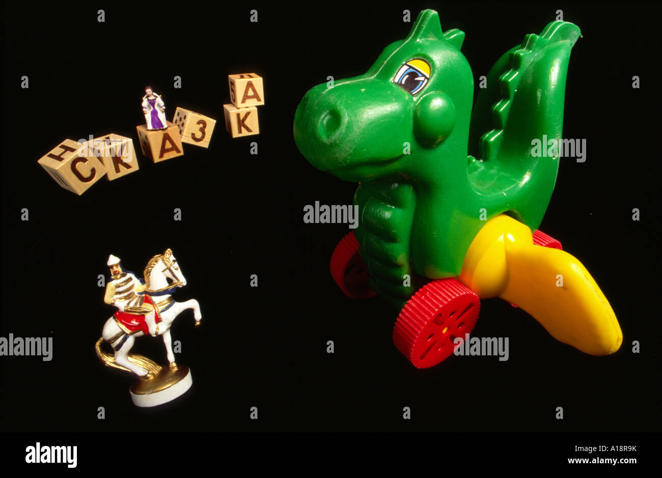 A still life of a plastic toy dragon with a knight on horseback and building blocks on a black background Stock Photo