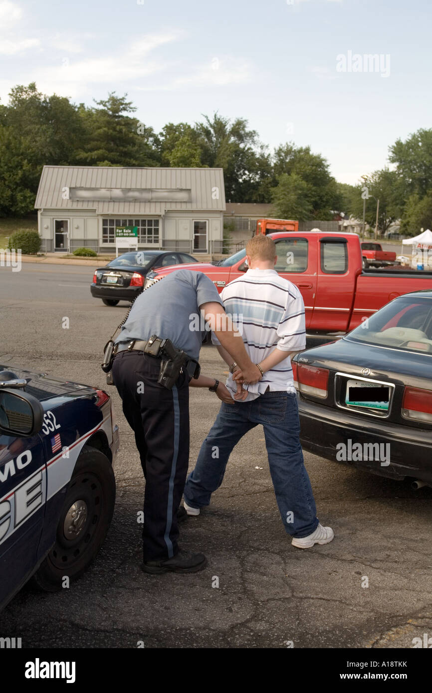 Police officer frisking suspect that was driving a vehicle that came up with non matching license plates. Kansas City, MO, USA. Stock Photo
