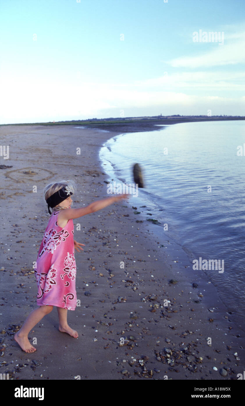 Girl aged 7 throwing sand into the water at Stone Point in Walton