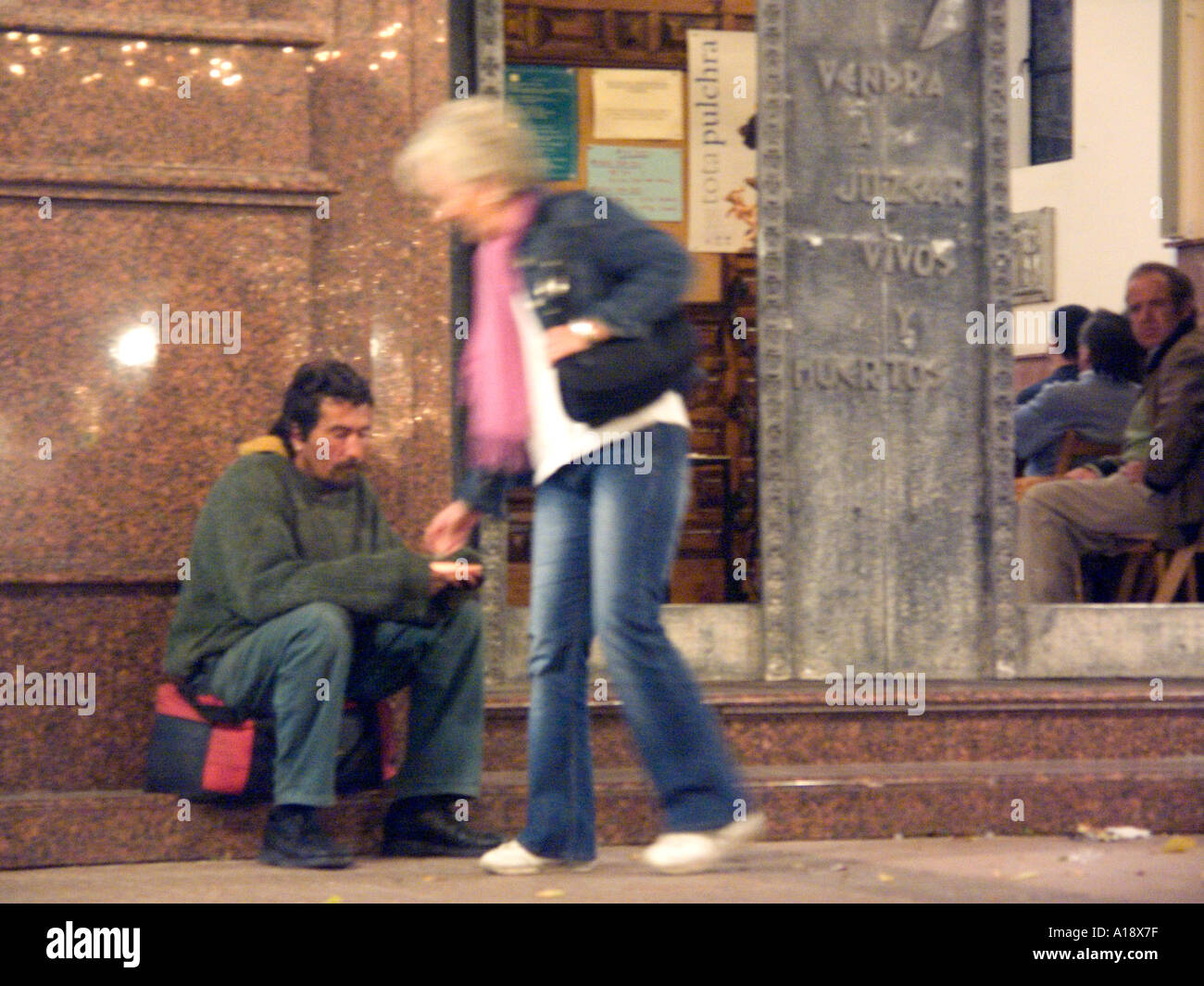 Spanish Homeless Beggar receives a money donation from a kind English lady outside a church at Christmas, homeless homelessness Stock Photo