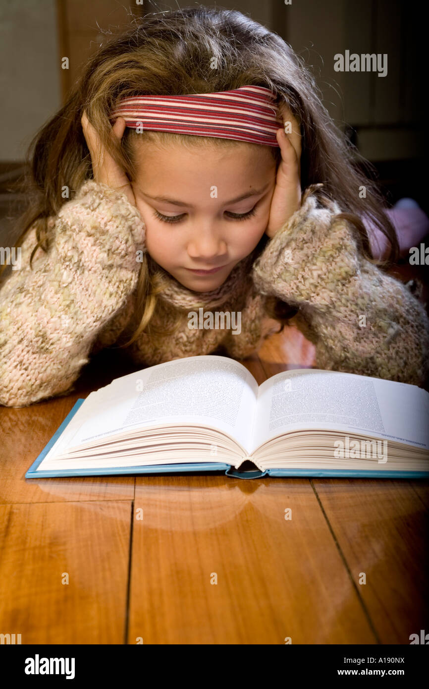 Concentrated schoolgirl on a book Stock Photo - Alamy