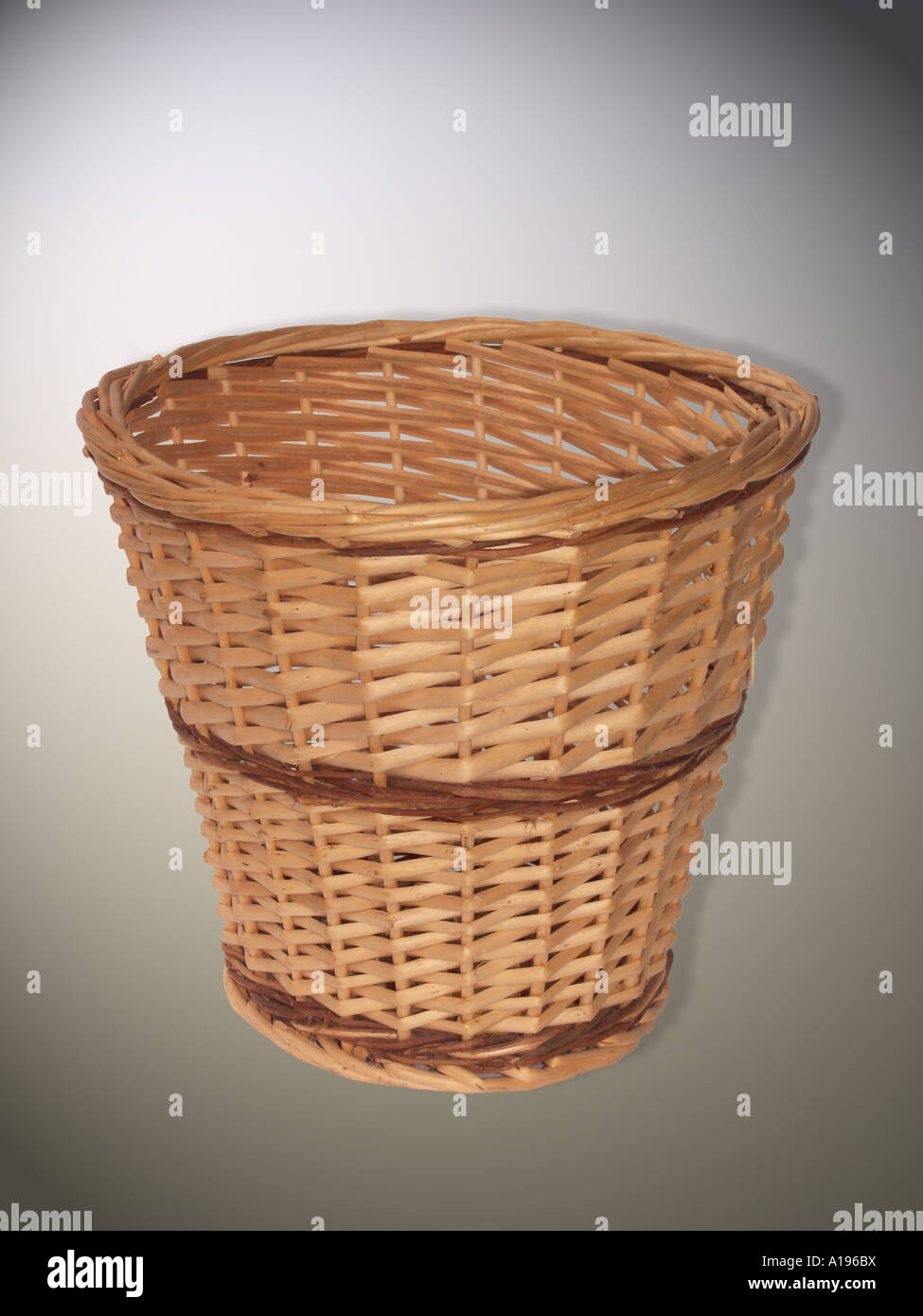 Brown woven wicker waste paper basket for use in office or home on light grey background Stock Photo