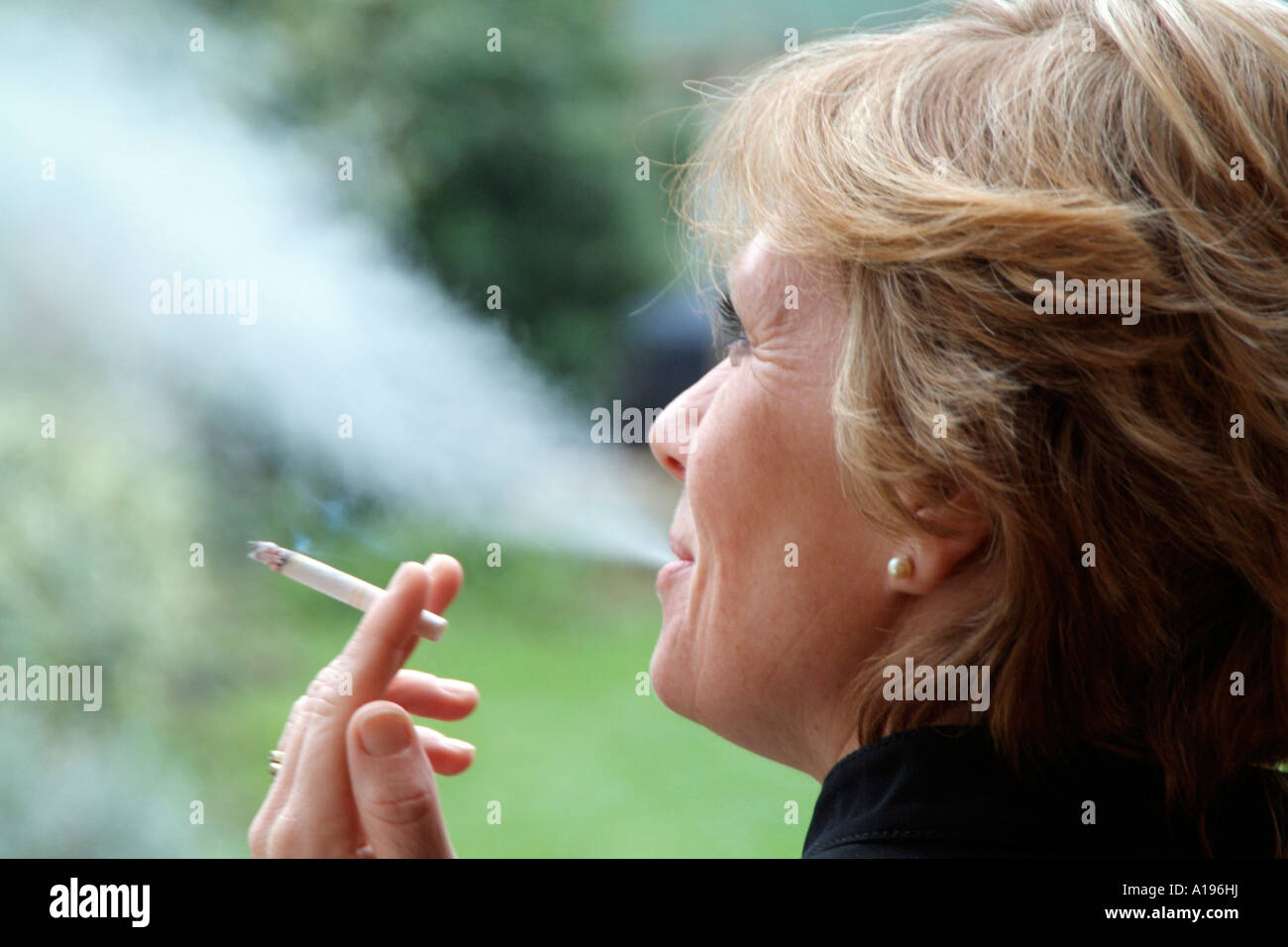 Woman smoking a cigarette Exhaling tobacco smoke Stock Photo