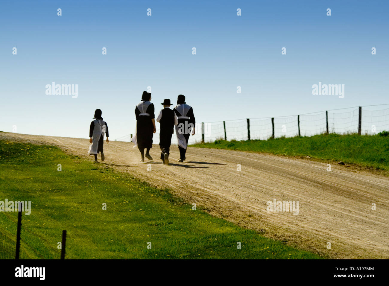 Amish family walking up a rural country road near Kalona, Iowa, wearing
