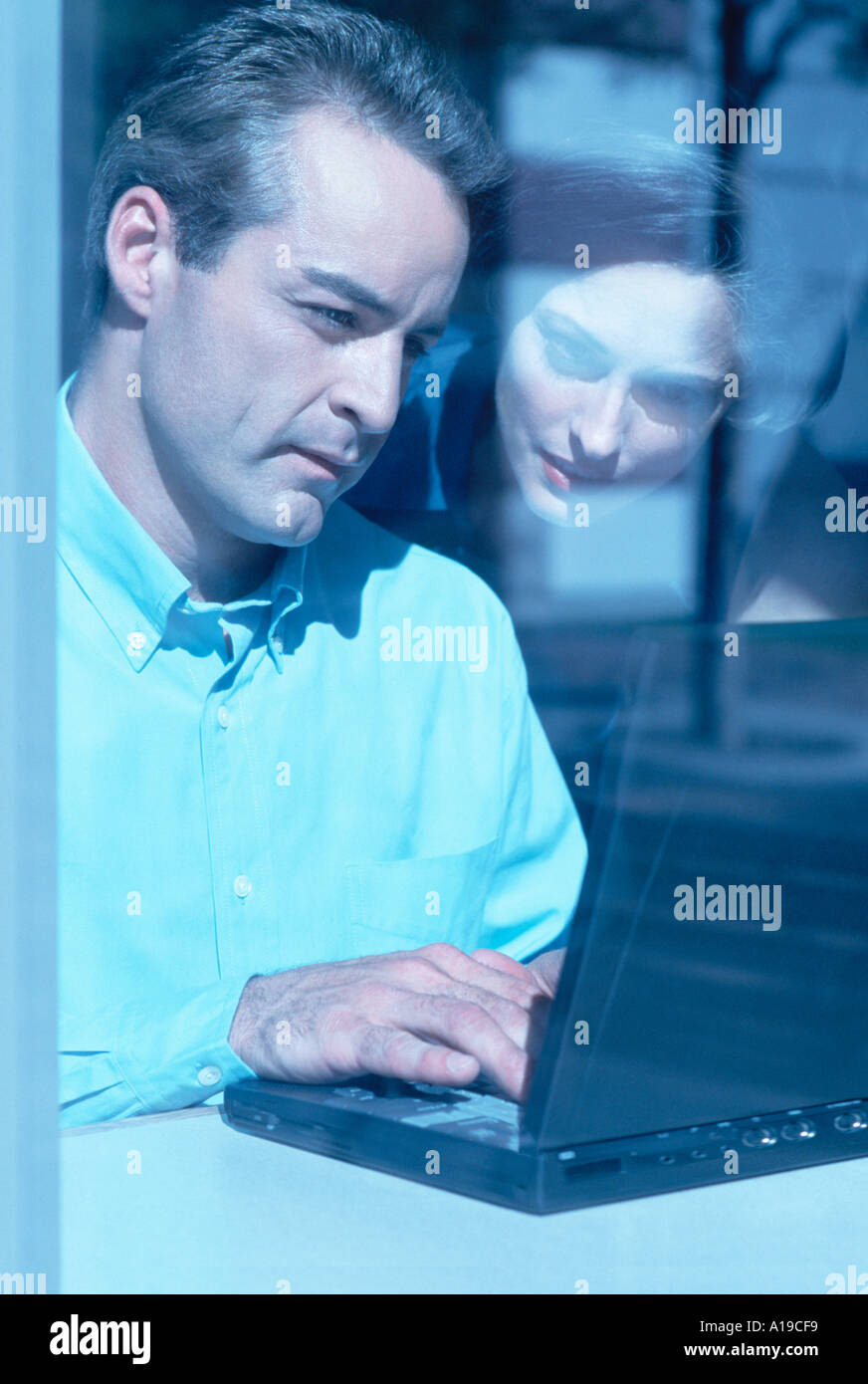Business partners working on laptop through window Stock Photo