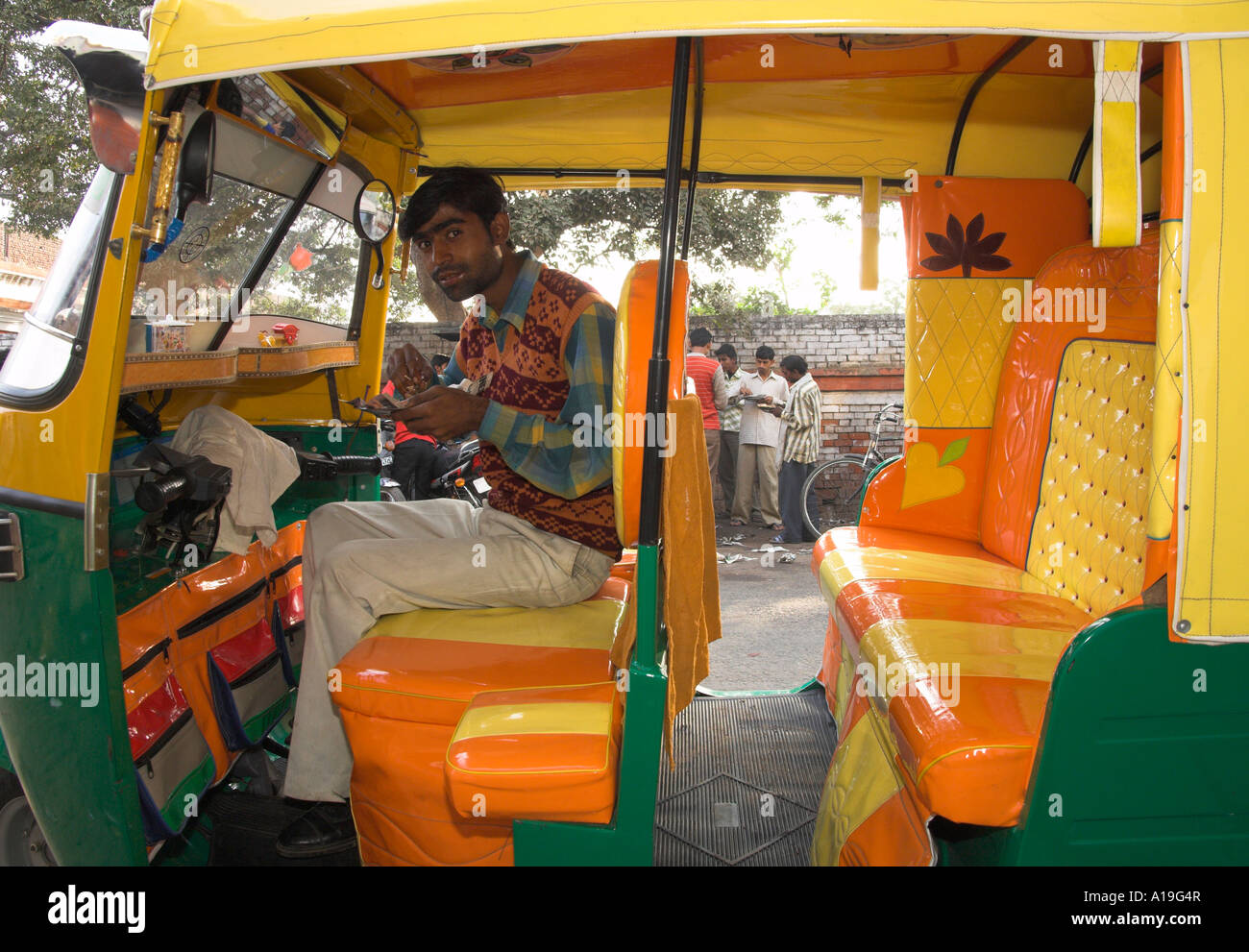 India Uttar Pradesh Agra street scene rickshaw owner sitting in his ...
