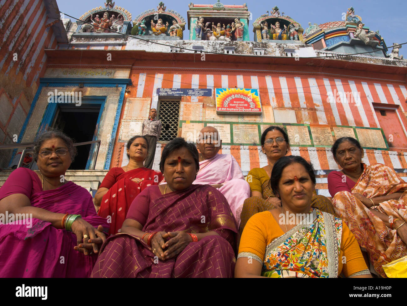 India Uttar Pradesh Ganges valley Varanassi group of women pilgrims sitting on the steps of Kedar ghat with temple in bkgd Stock Photo
