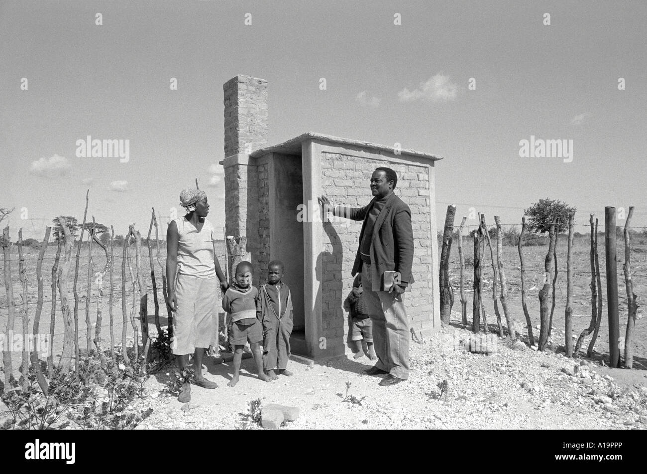 B/W of a family standing beside their new ventilated pit latrine in a rural area. Nr. Gweru, Zimbabwe Stock Photo