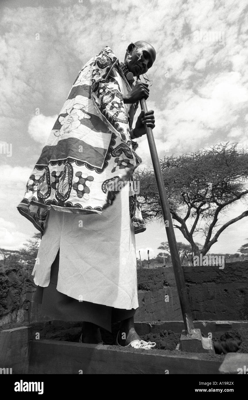 B/W of a Maasai woman in traditional dress building a rammed earth adobe house, a new technique for longer lasting buildings.Kajiado, Kenya Stock Photo
