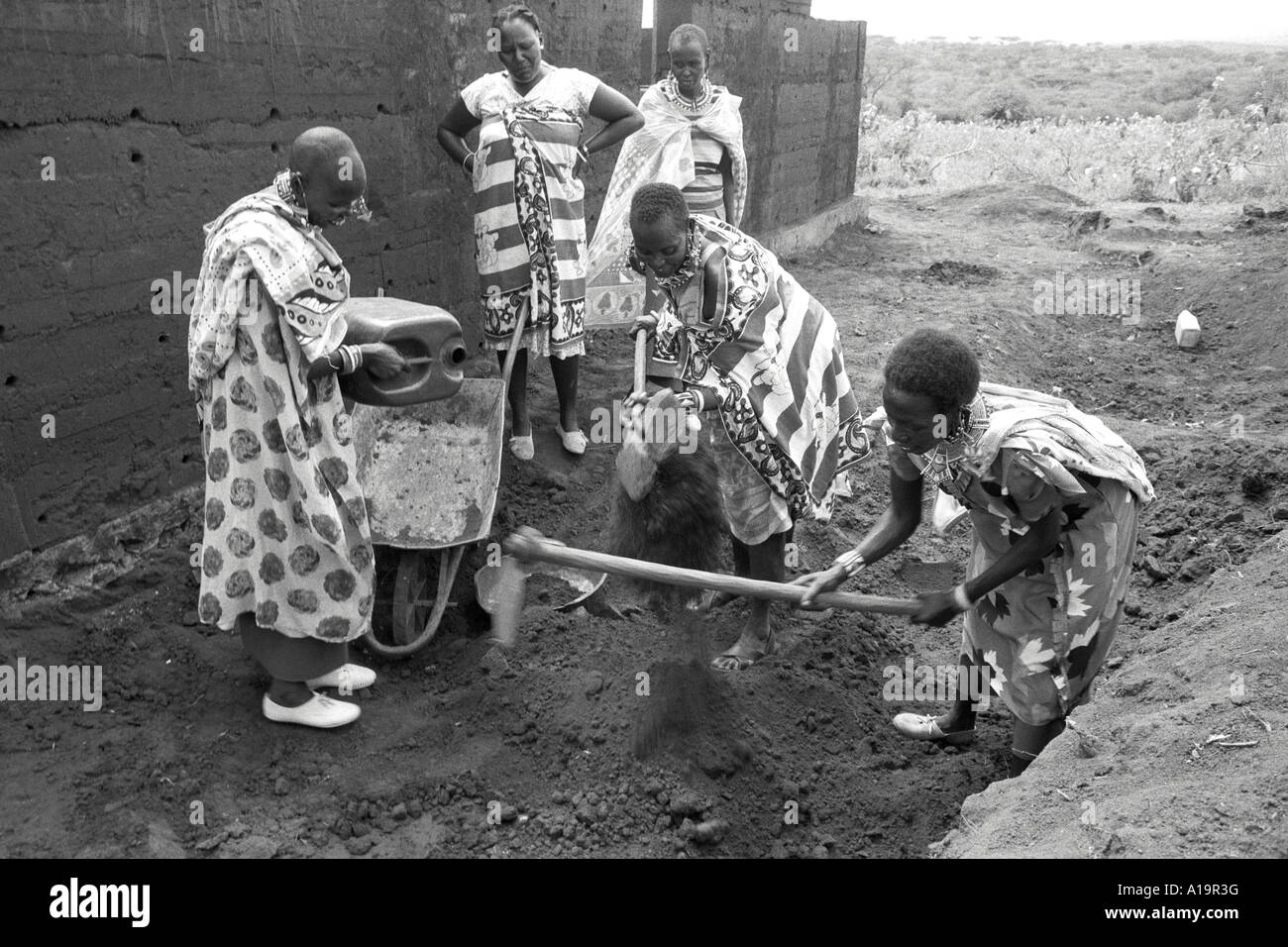 B/W of Maasai women in traditional dress building a rammed earth adobe house. Kadiado, Kenya Stock Photo