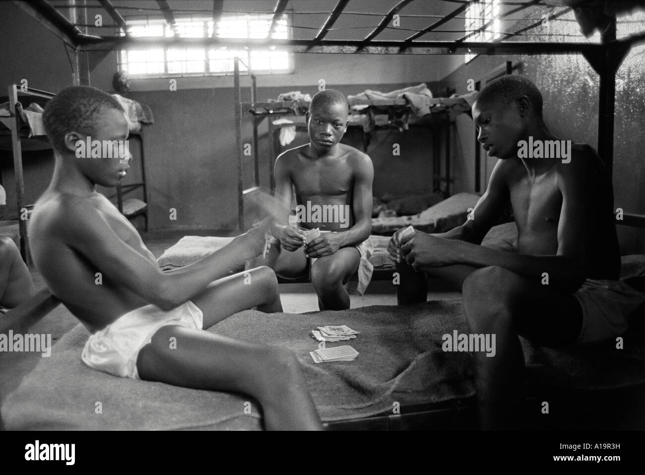 B/W of three young convicted male offenders playing cards in their cell in a detention centre. Kampala,  Uganda Stock Photo