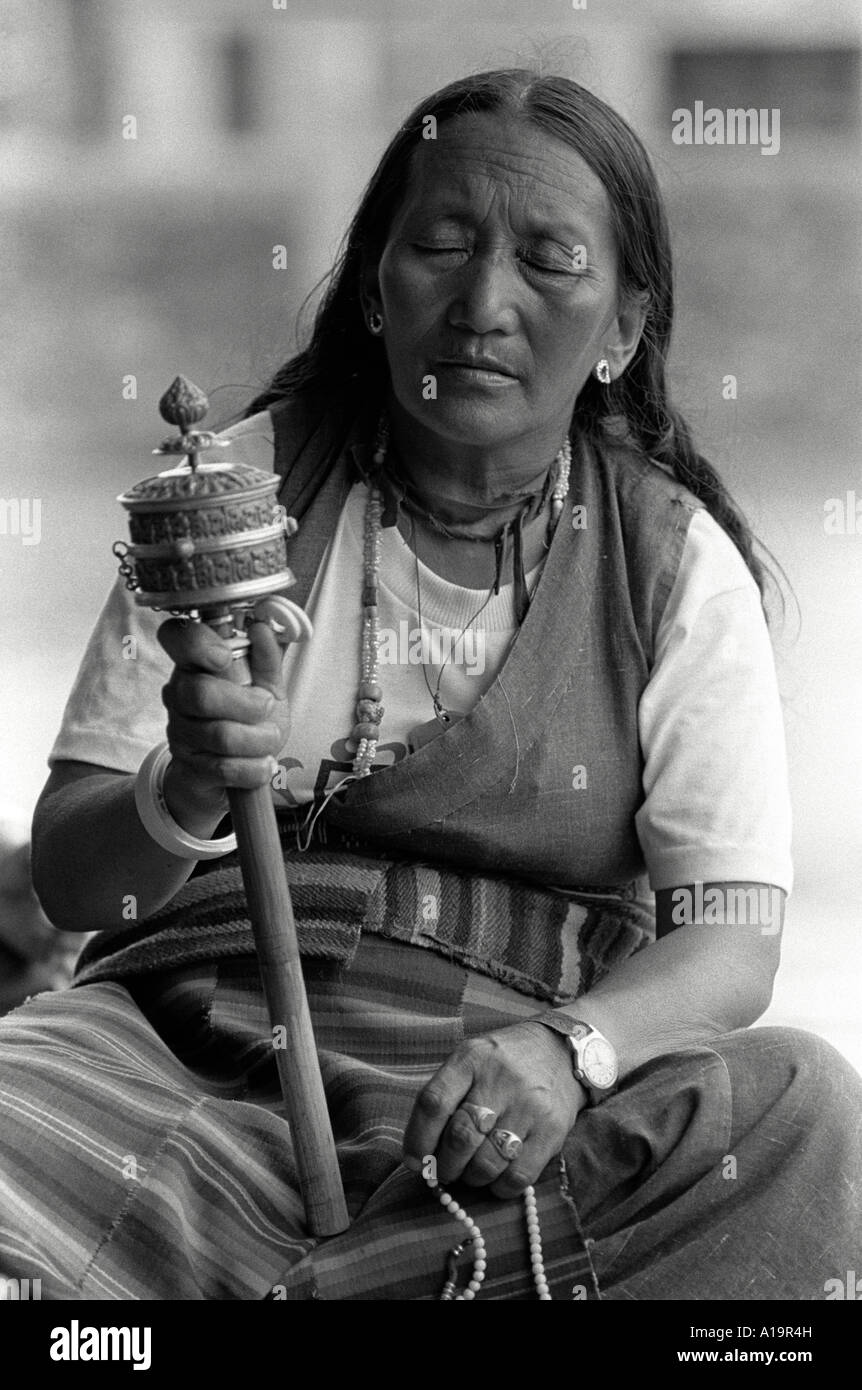 B/W portrait of a female Tibetan refugee in traditional dress spinning her prayer wheel. Nepal Stock Photo