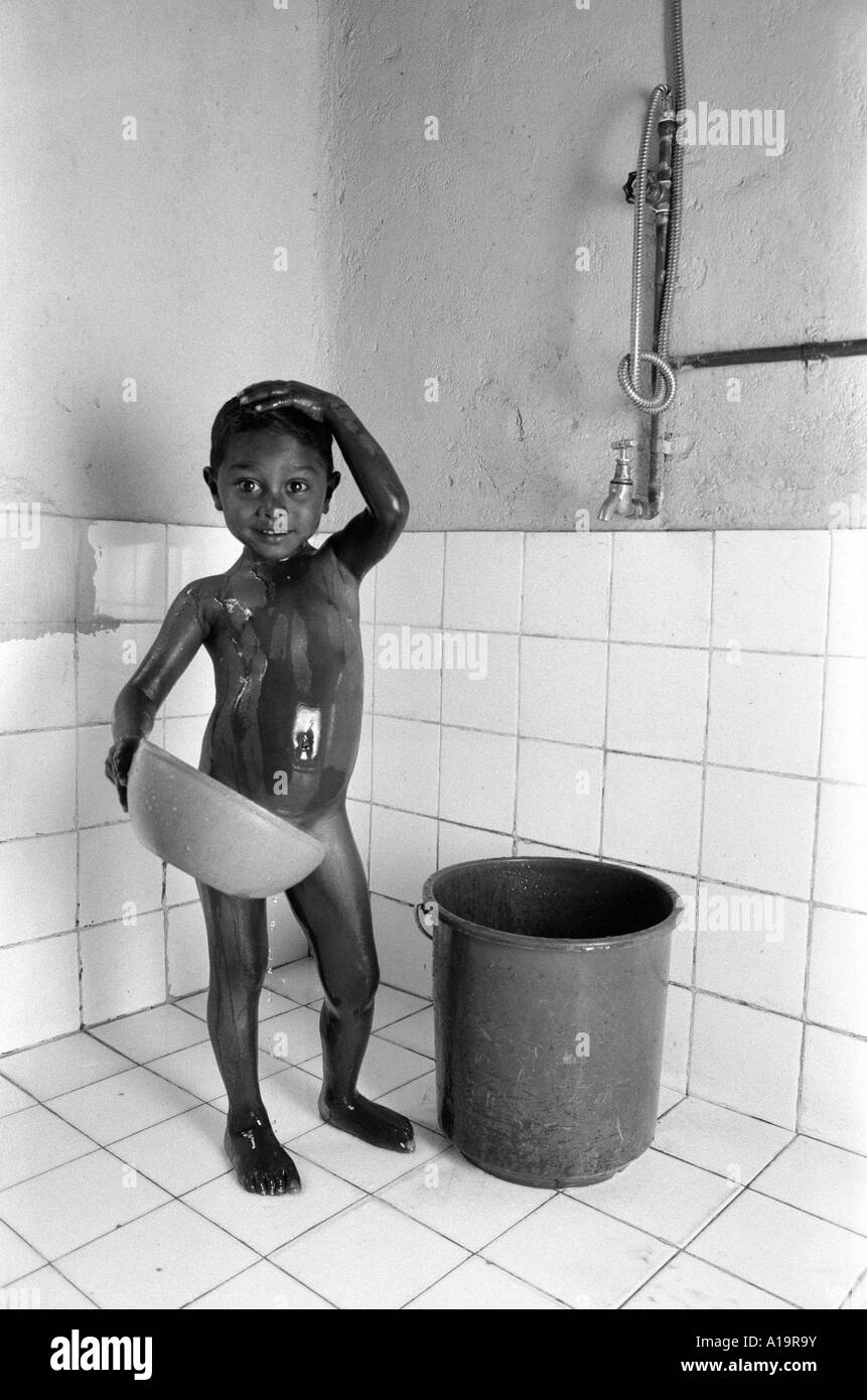 Boy showering in new bathroom funded by UK charity for tea estate workers, Sri Lanka Stock Photo
