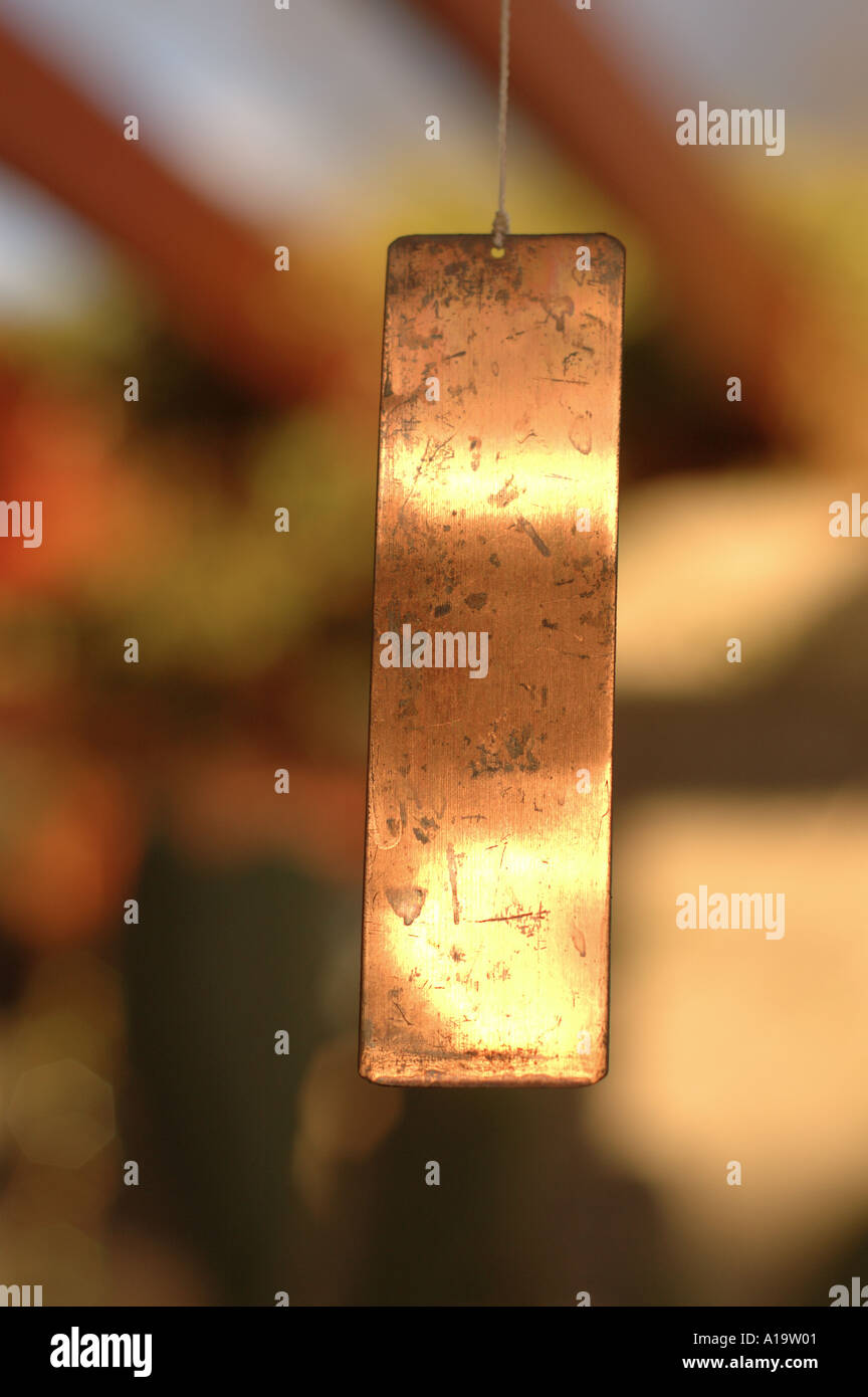 Copper wind chime in sunlight with blurred background Stock Photo Alamy