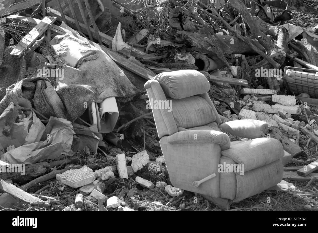Black and while image of a discarded reclining chair in a trash pile