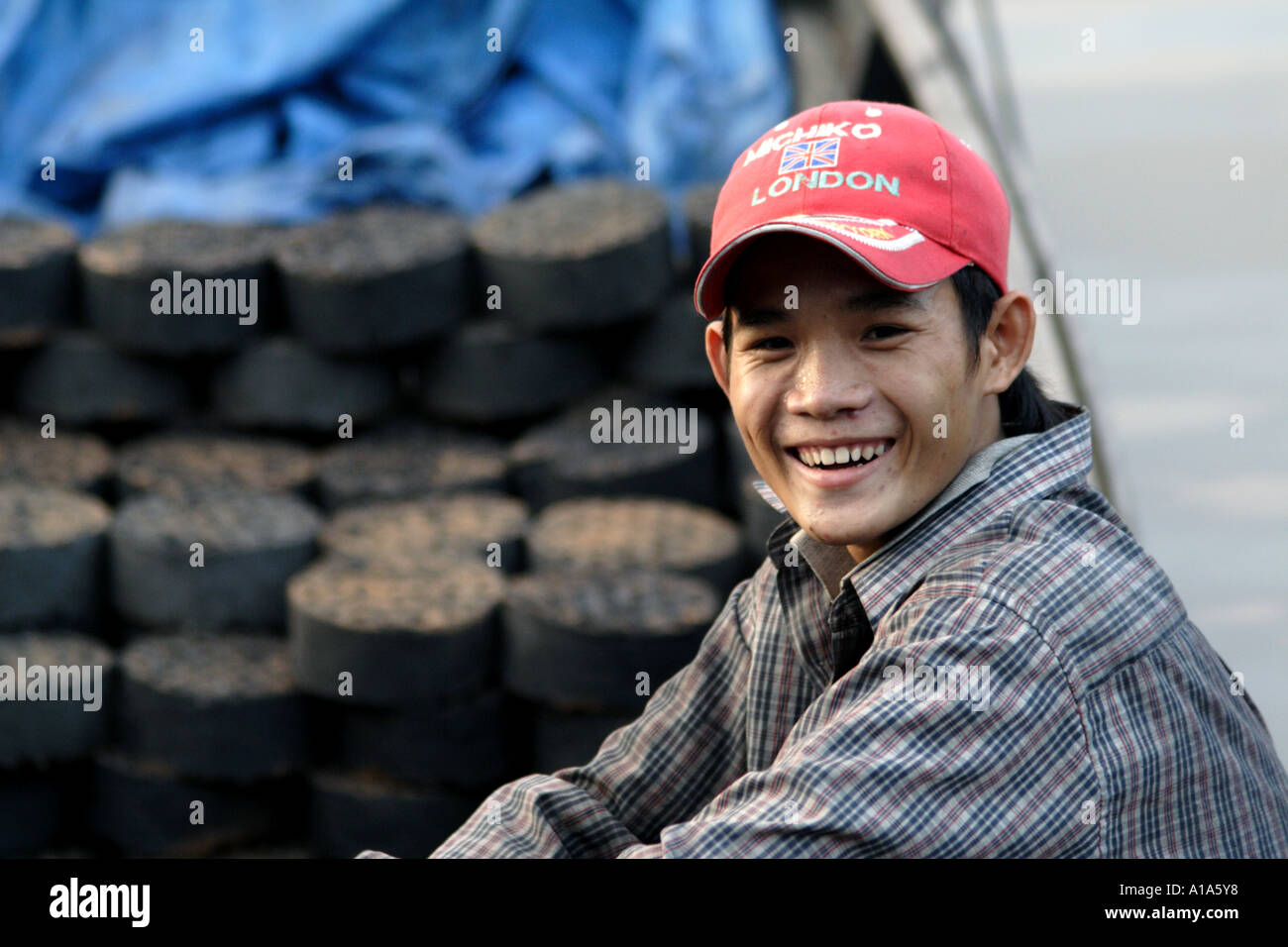 Young man delivering heating coal by boat on the Mekong Delta, Vietnam Stock Photo