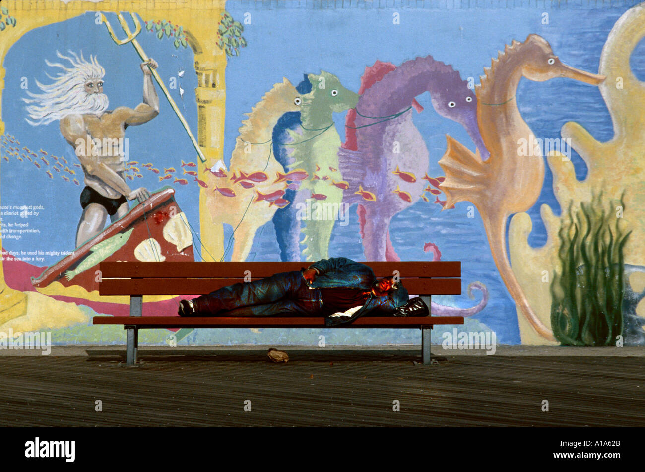 A man sleeping on a bench at Coney Island New York USA against a ...