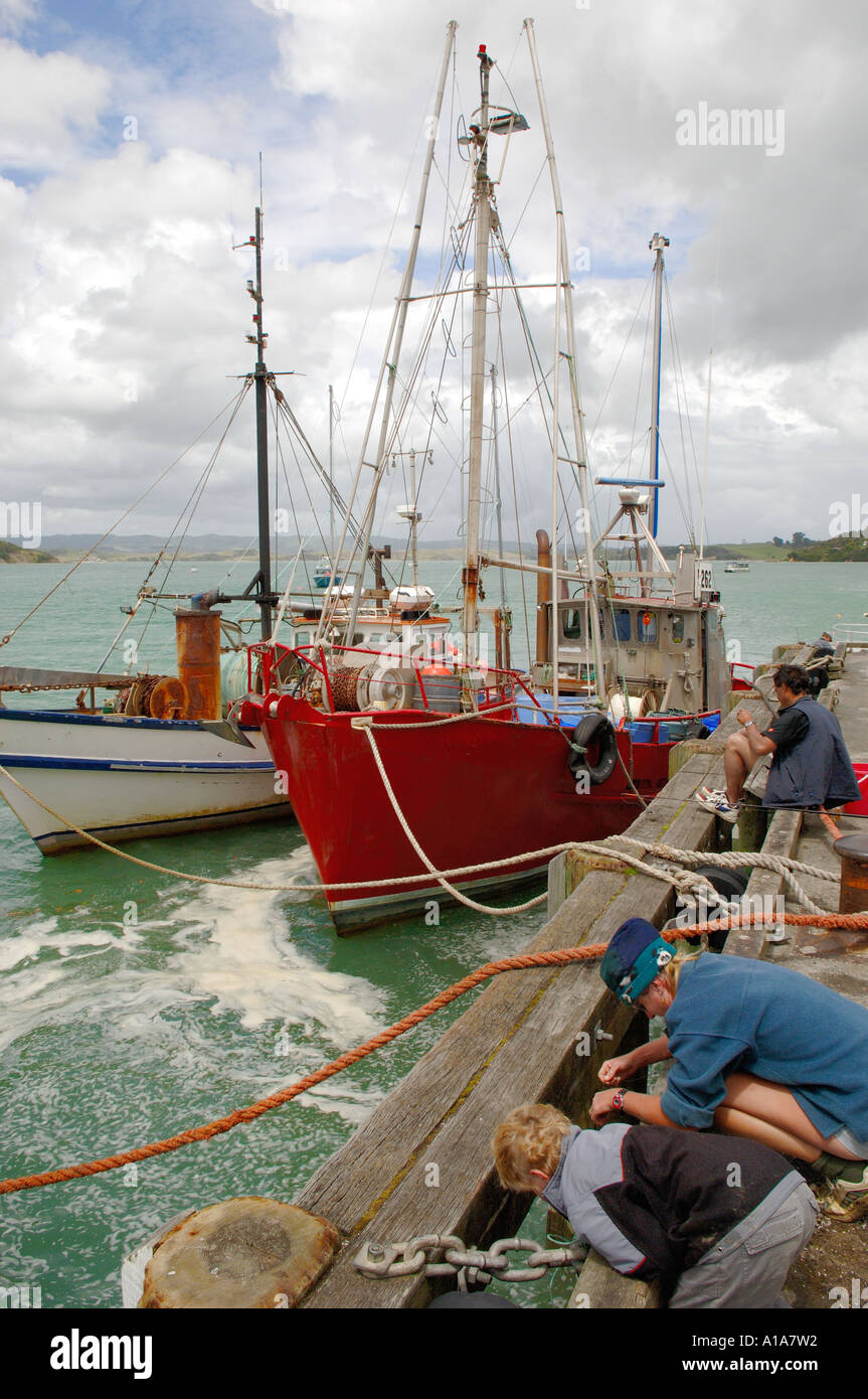 Boys fishing off the wharf, town of Raglan, Waikato, North Island New Zealand Stock Photo