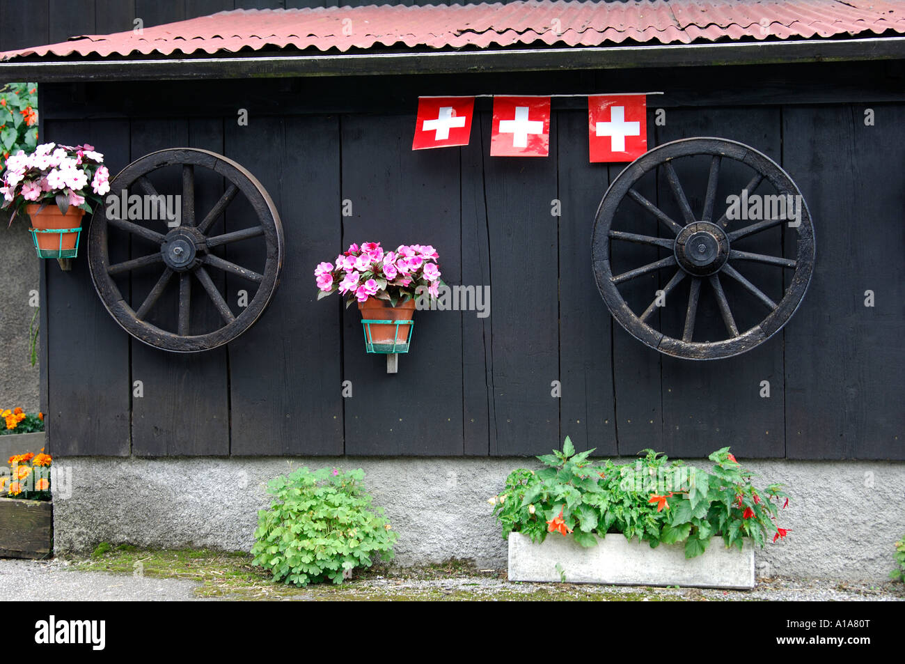 Swiss Patriotism, flowers, cart wheels and Swis flag, Bernense Oberland, Switzerland Stock Photo