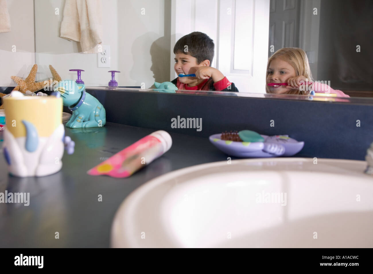 Reflection in mirror of brother and sister brushing teeth Stock Photo ...