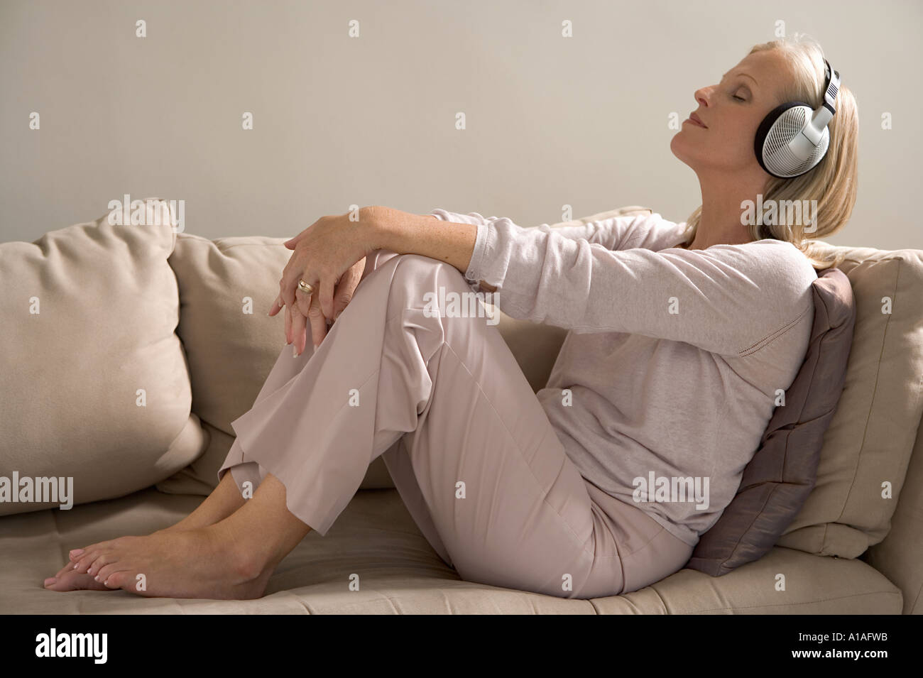 Woman on sofa wearing haedphones Stock Photo