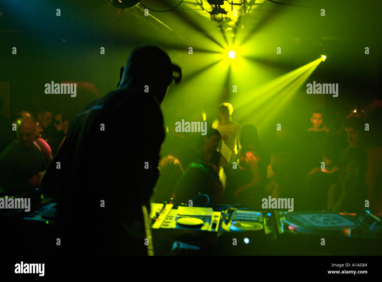 Club DJ Behind the Decks of a Crowded Nightclub. Stock Photo