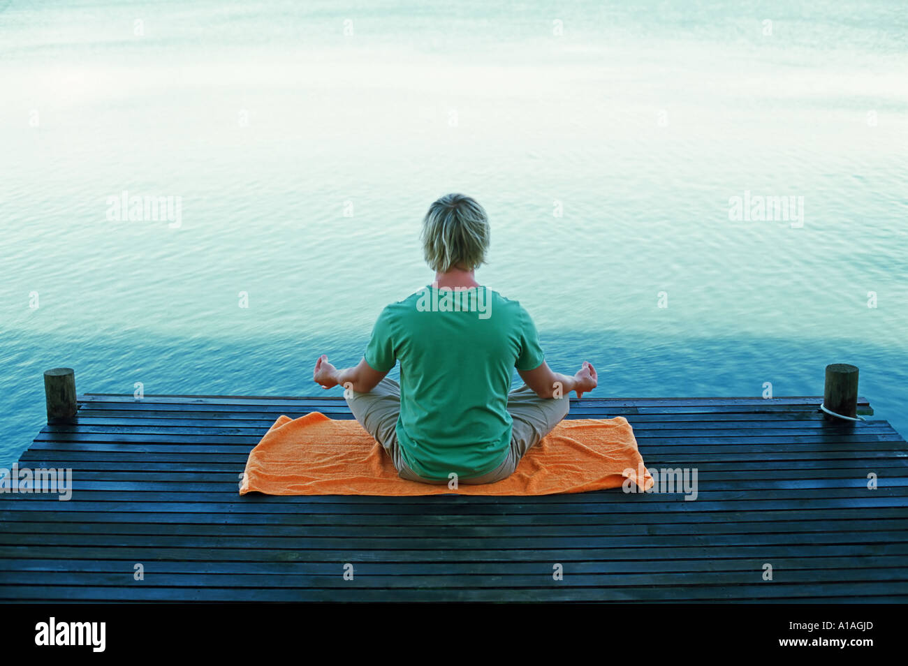 Man meditating by water Stock Photo