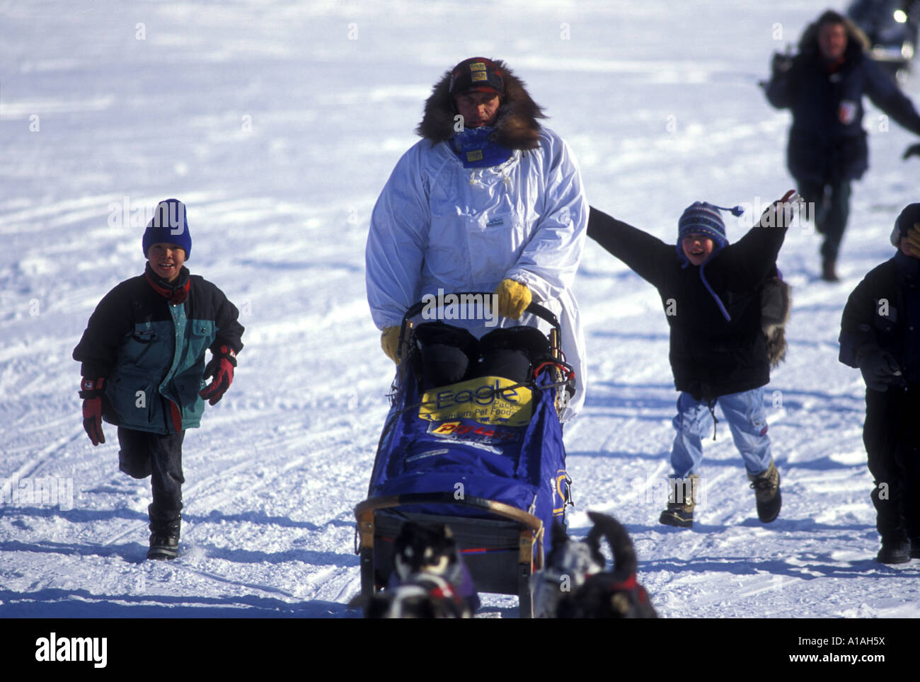 USA Alaska Unalakleet Yupik Eskimo boys run with musher Martin Buser into town during Iditarod sled dog race Stock Photo