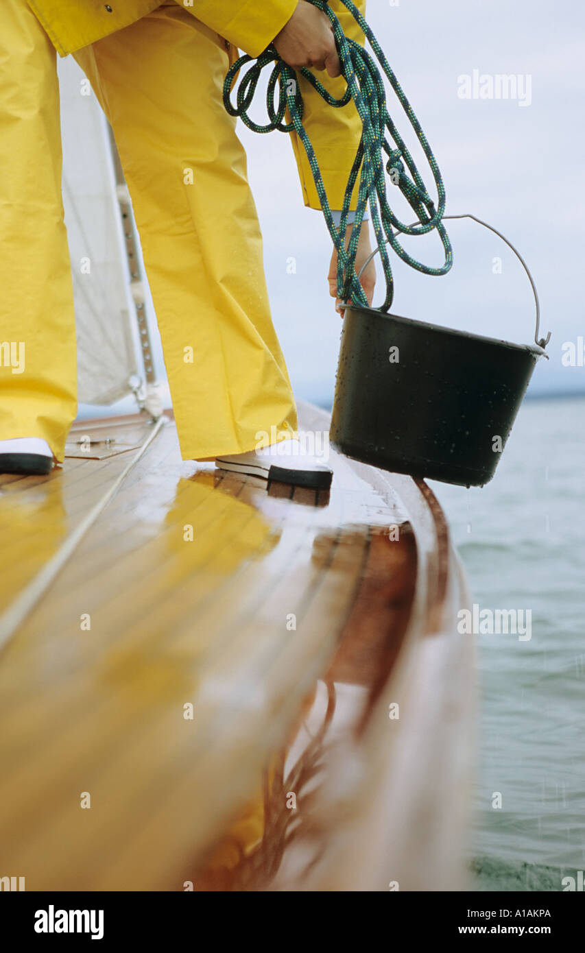 Person on deck of boat holding bucket and rope Stock Photo