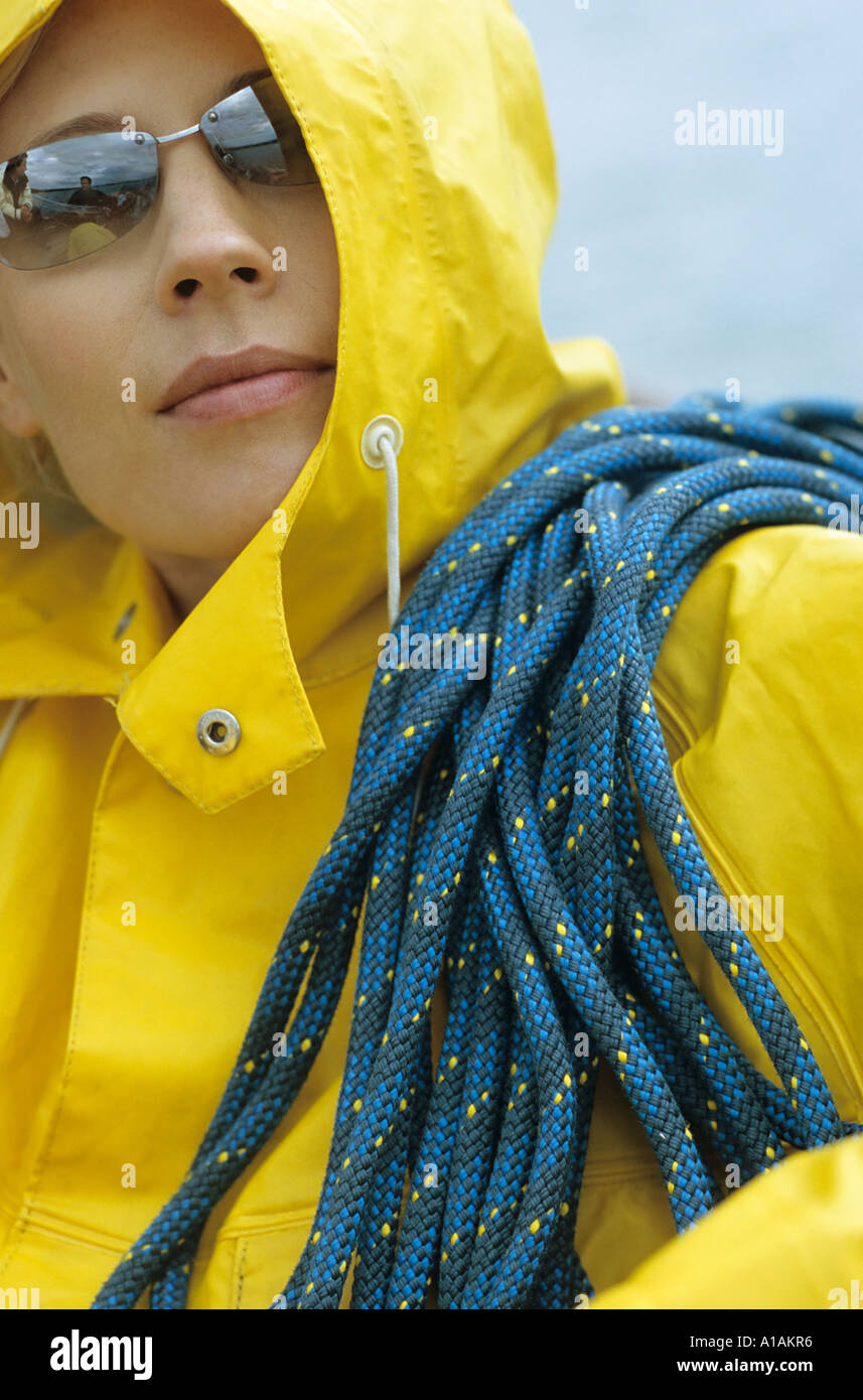 Woman in yellow raincoat and sunglasses with rope over her shoulder Stock Photo