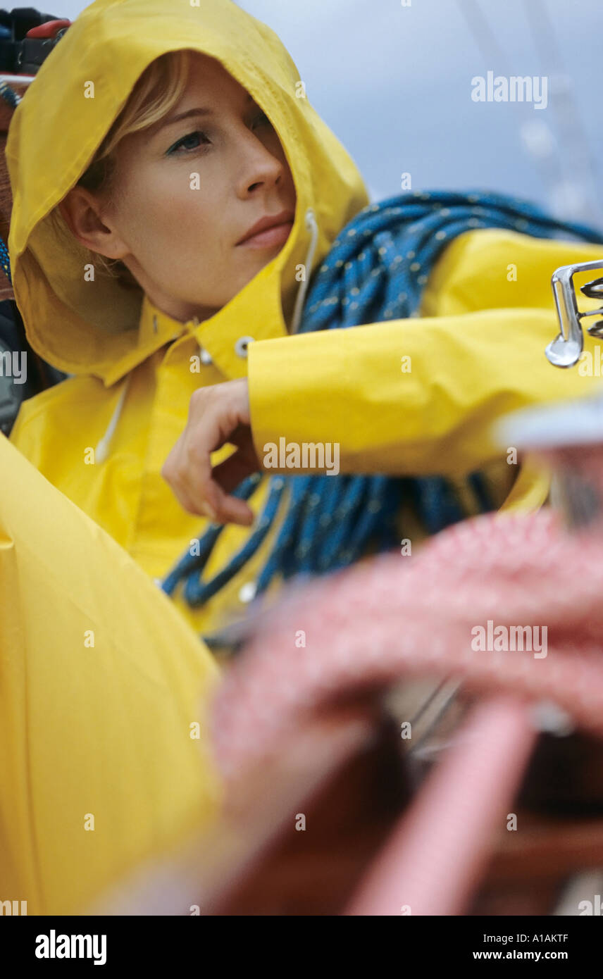 Woman in yellow raincoat carrying rope Stock Photo