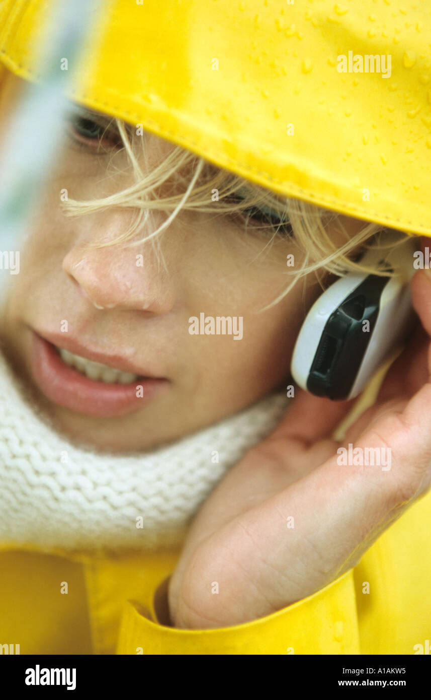 Close-up of woman in yellow raincoat using mobile phone Stock Photo