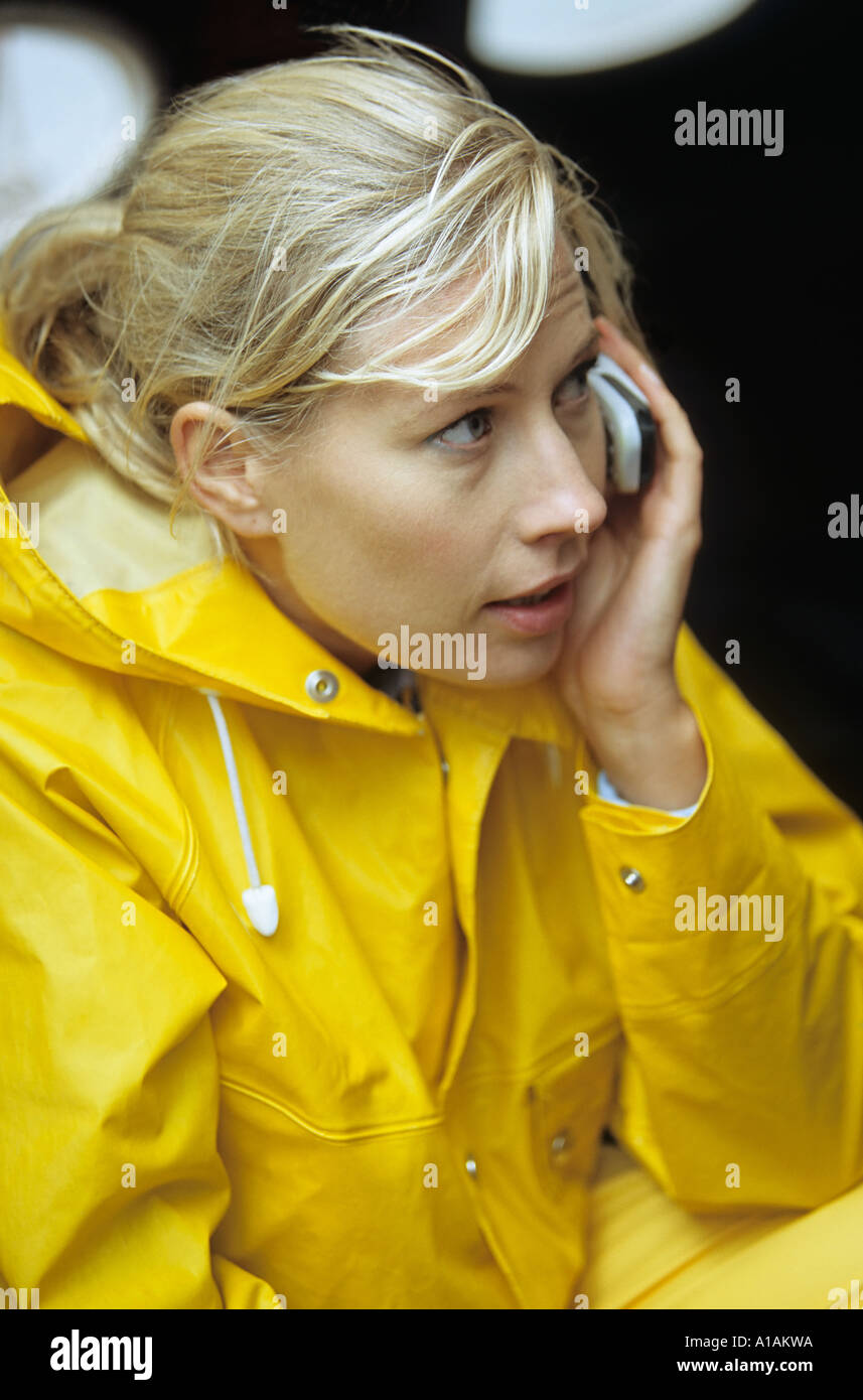 Woman in yellow raincoat using mobile phone Stock Photo