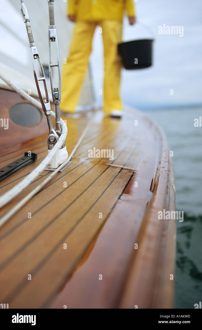 Person standing on deck of boat holding bucket Stock Photo