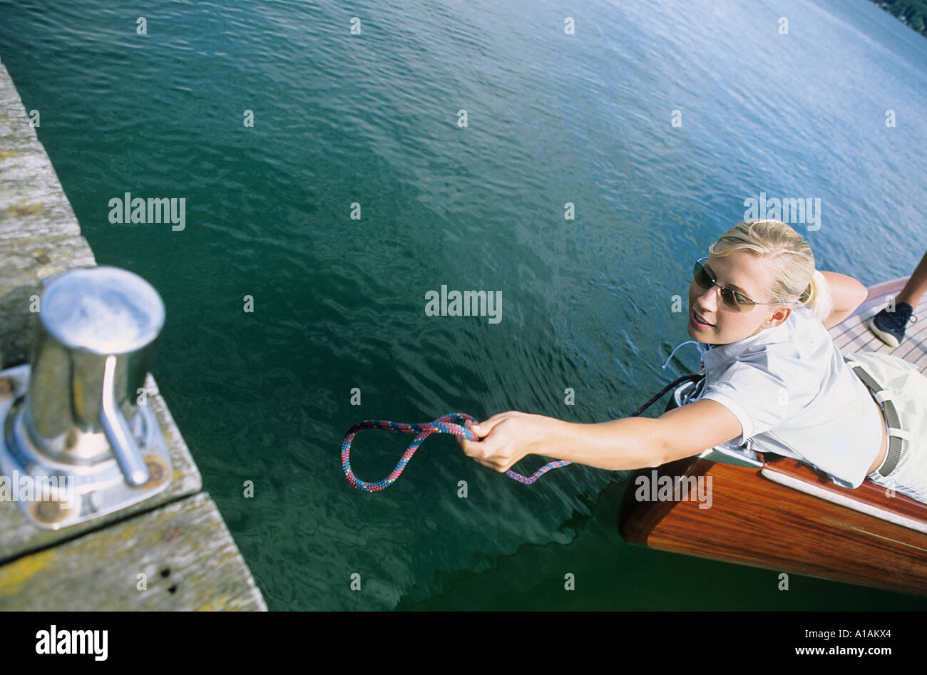 Woman on boat reaching for jetty Stock Photo