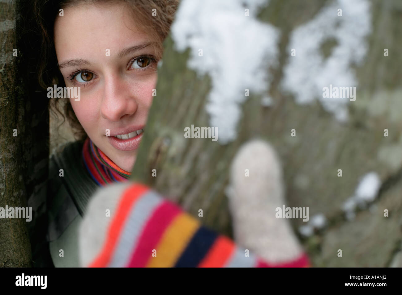 Woman in gloves behind a tree Stock Photo