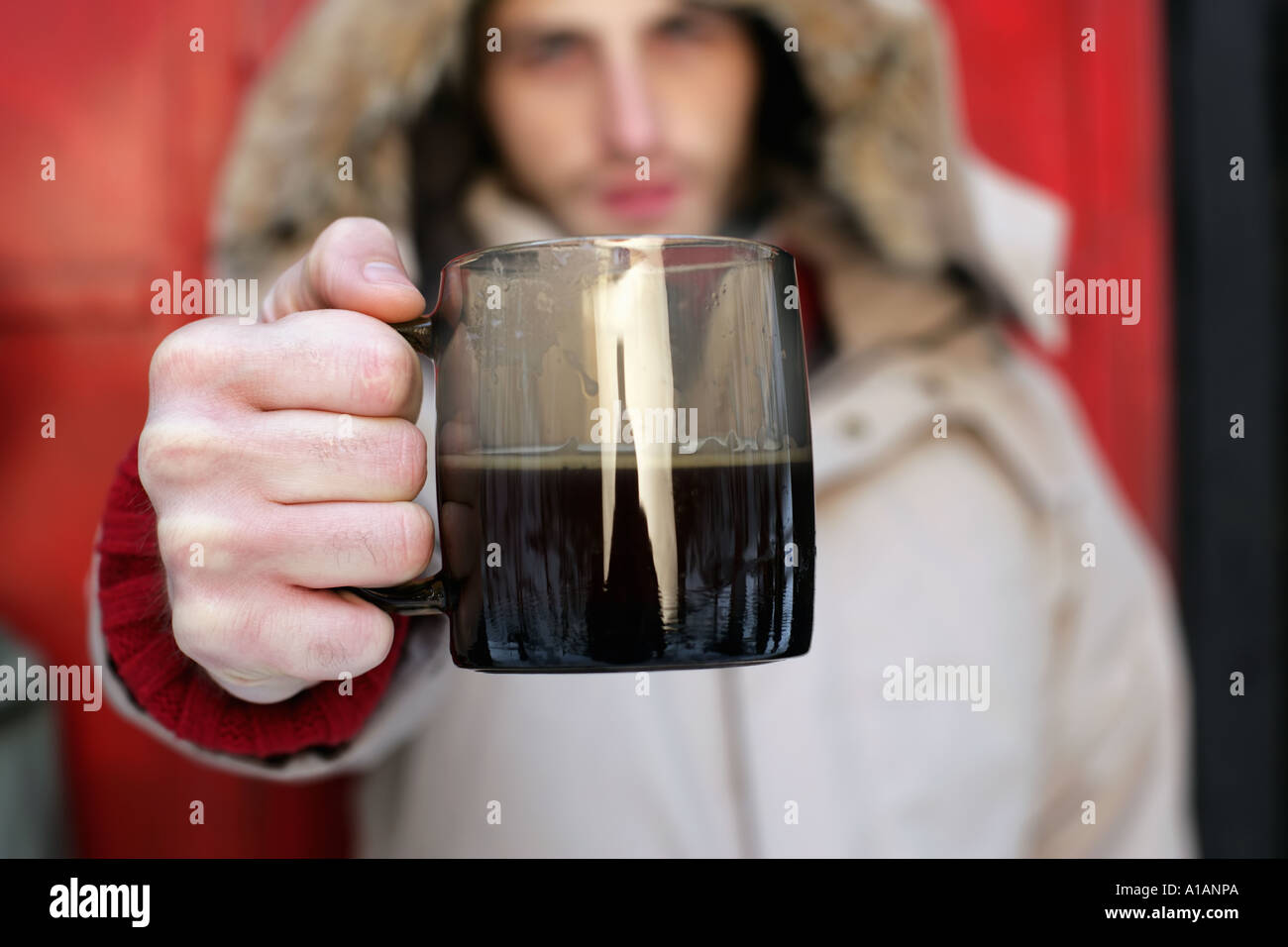 Man in a coat holding a coffee cup Stock Photo