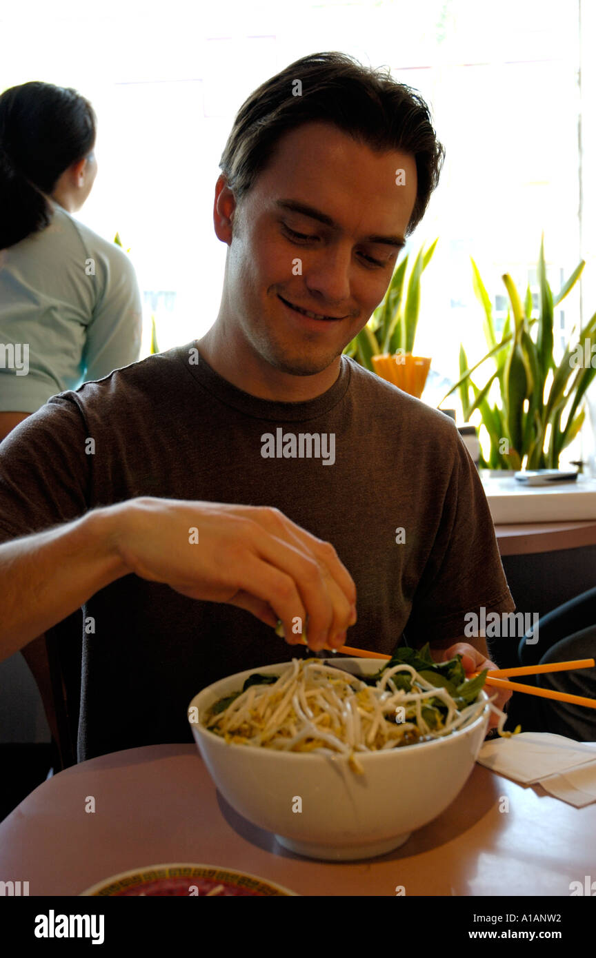 https://c8.alamy.com/comp/A1ANW2/young-american-man-eating-chinese-noodle-soup-squeezing-lemon-into-A1ANW2.jpg
