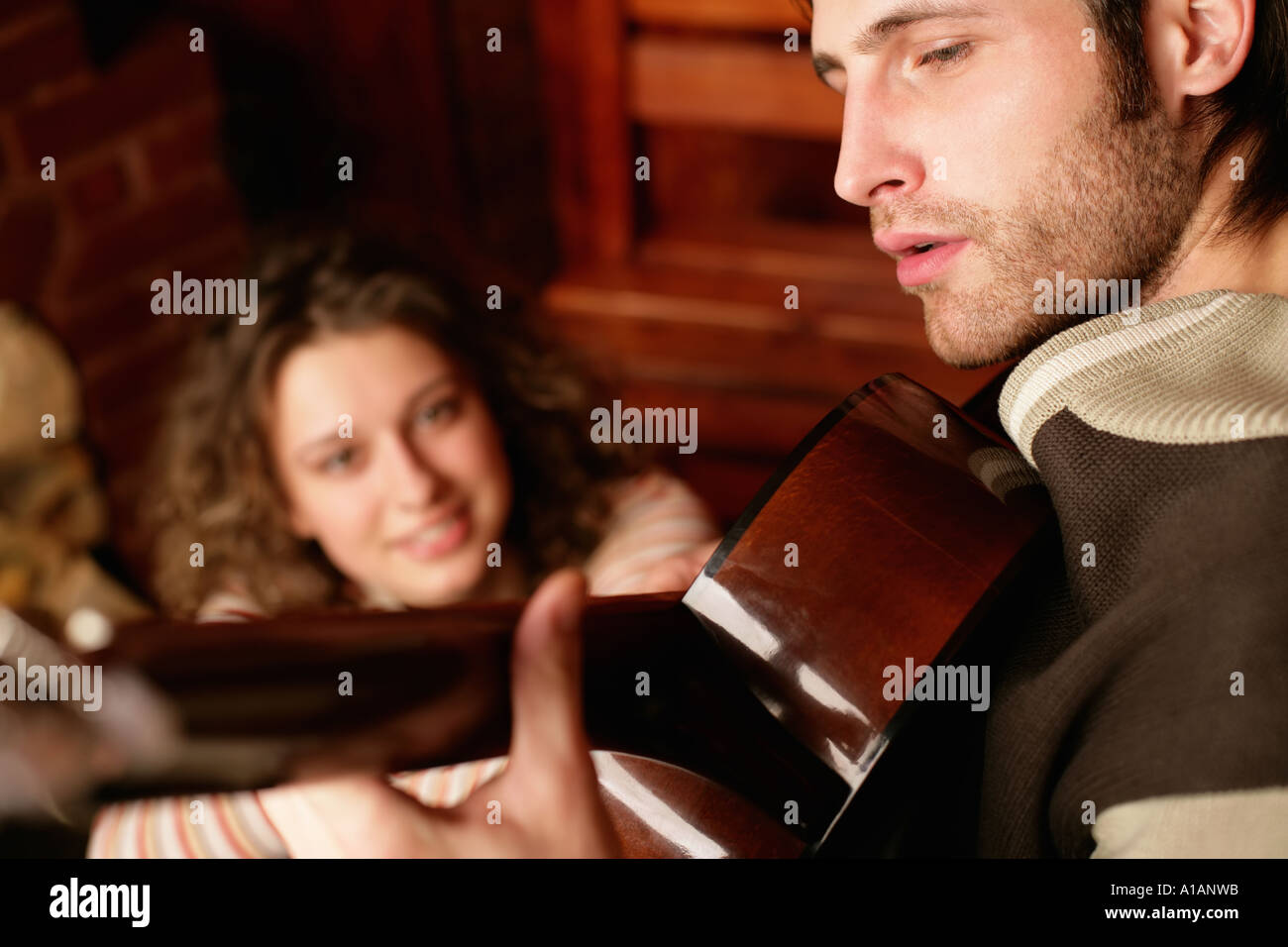 Woman listening to man play guitar Stock Photo