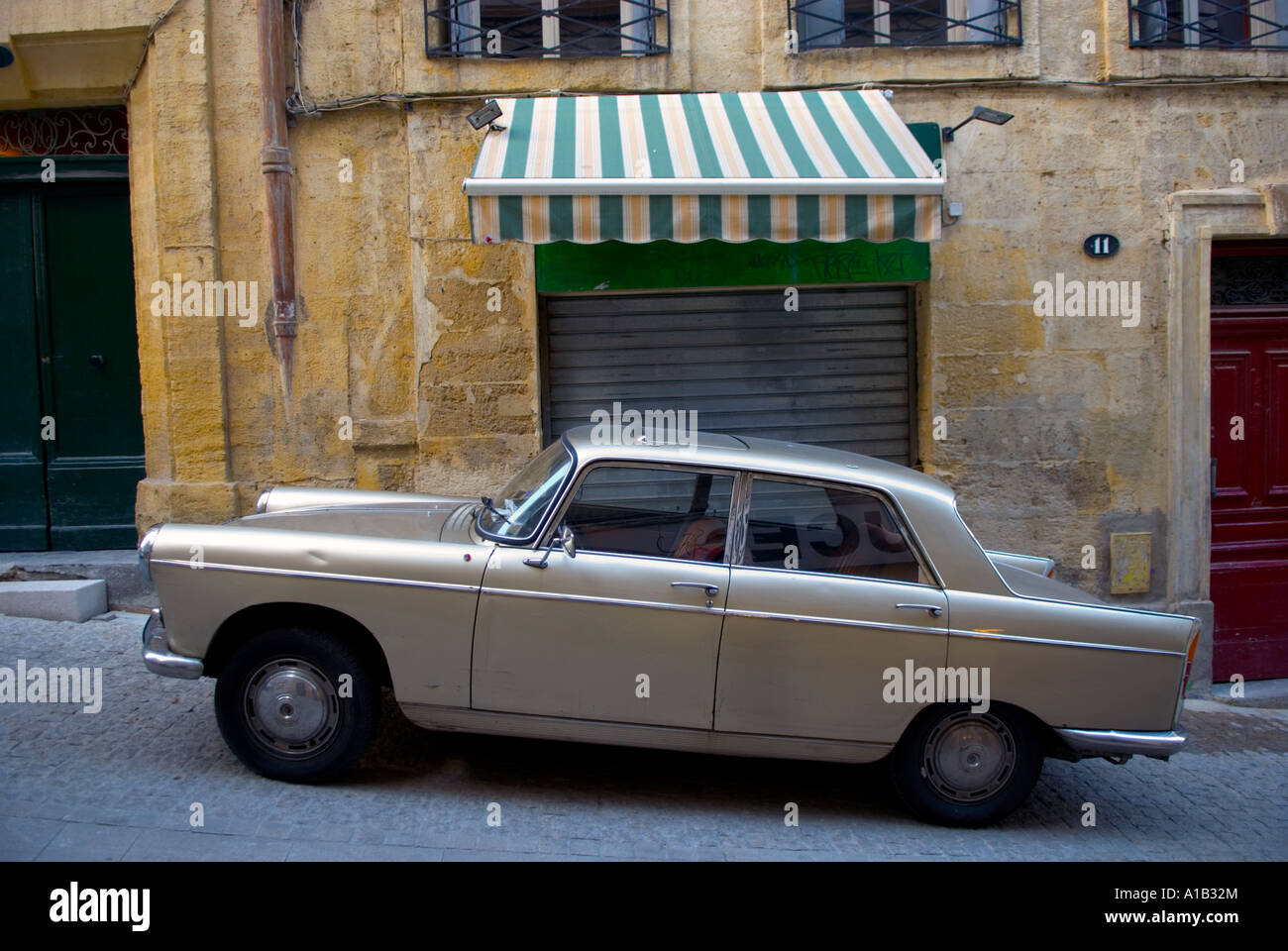 a vintage french car parked in front of a  closed shop on a slope Stock Photo