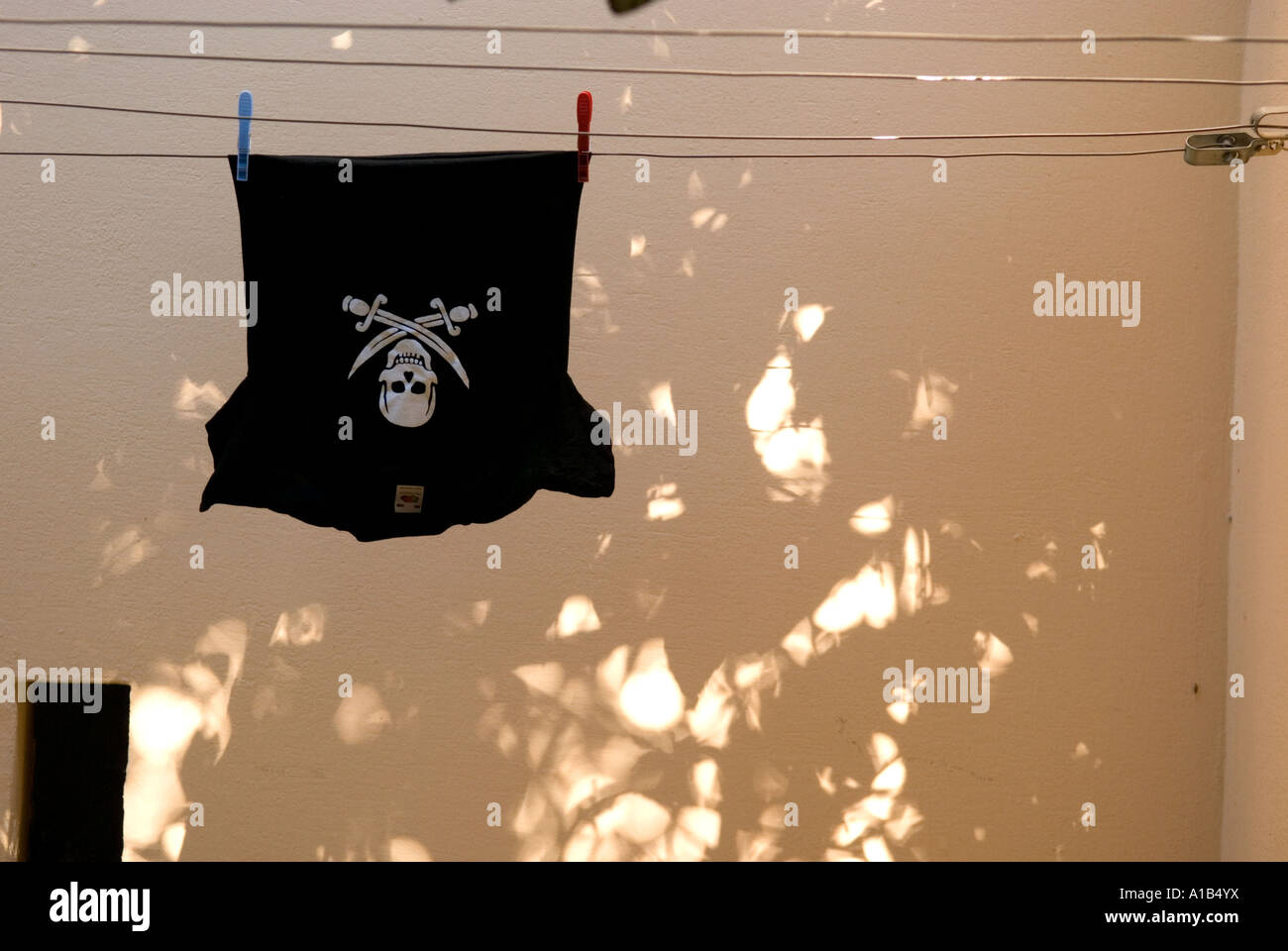 a kids black t-shirt with a white skull and crossbones hangs to dry on a washing line Stock Photo